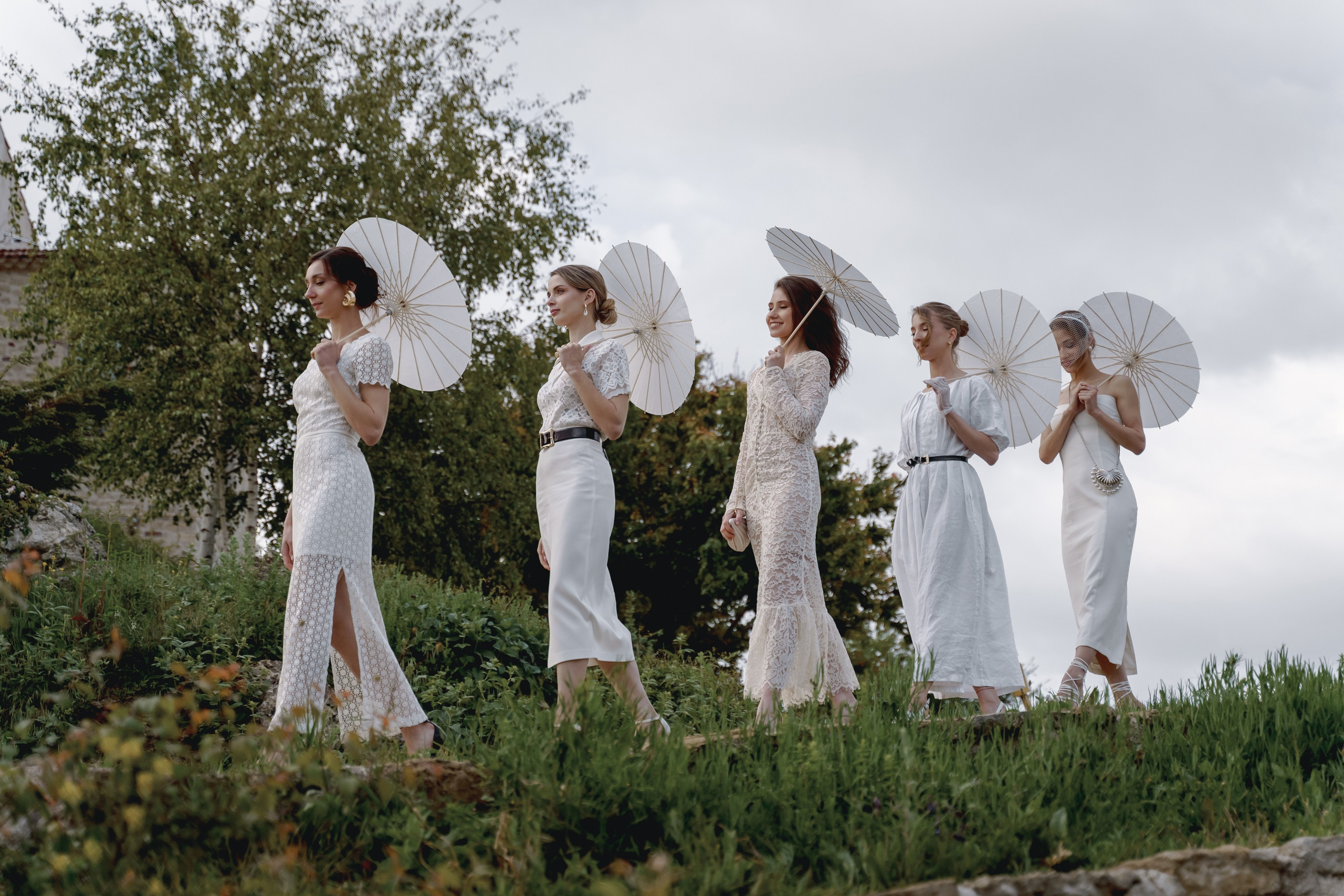 Гости в светлых платьях и зонтами летом на винодельне в Анапе