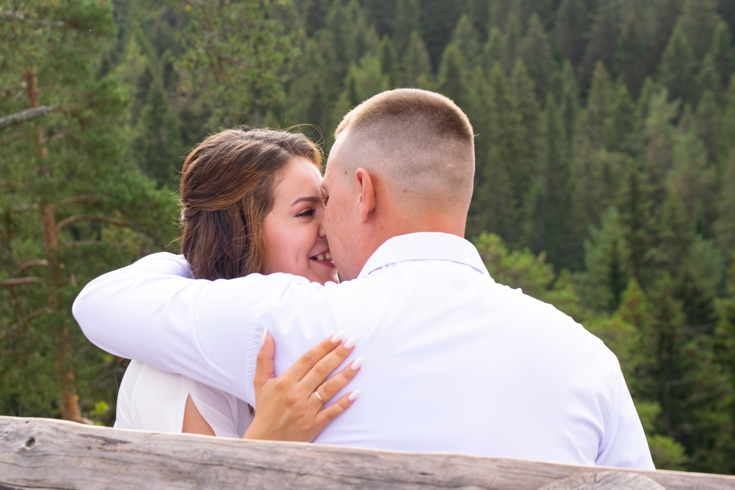 Свадебная фотосъемка на горе Паасо Сортавала. Жених и невеста целуются на фоне леса.