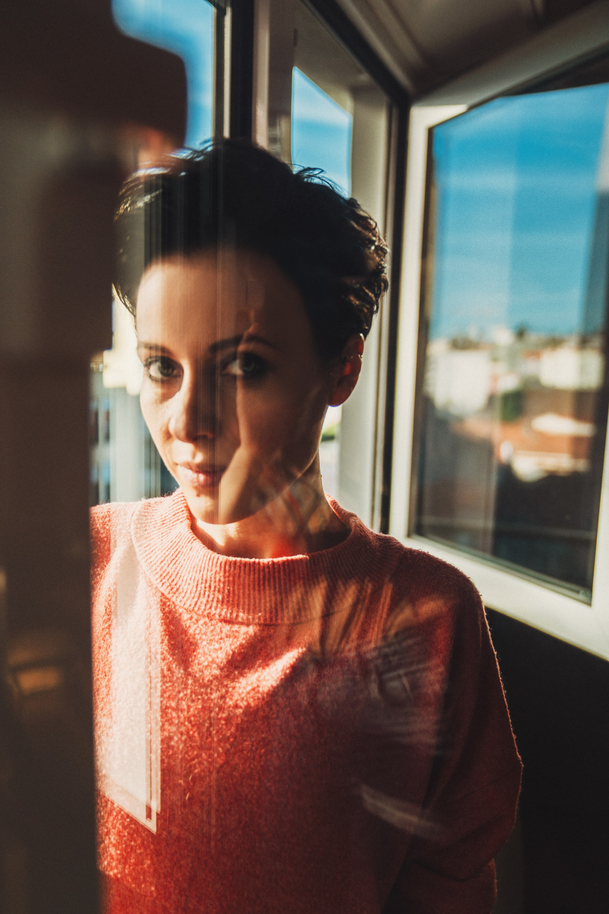 Лицо девушки в окне с бликами и отражениями