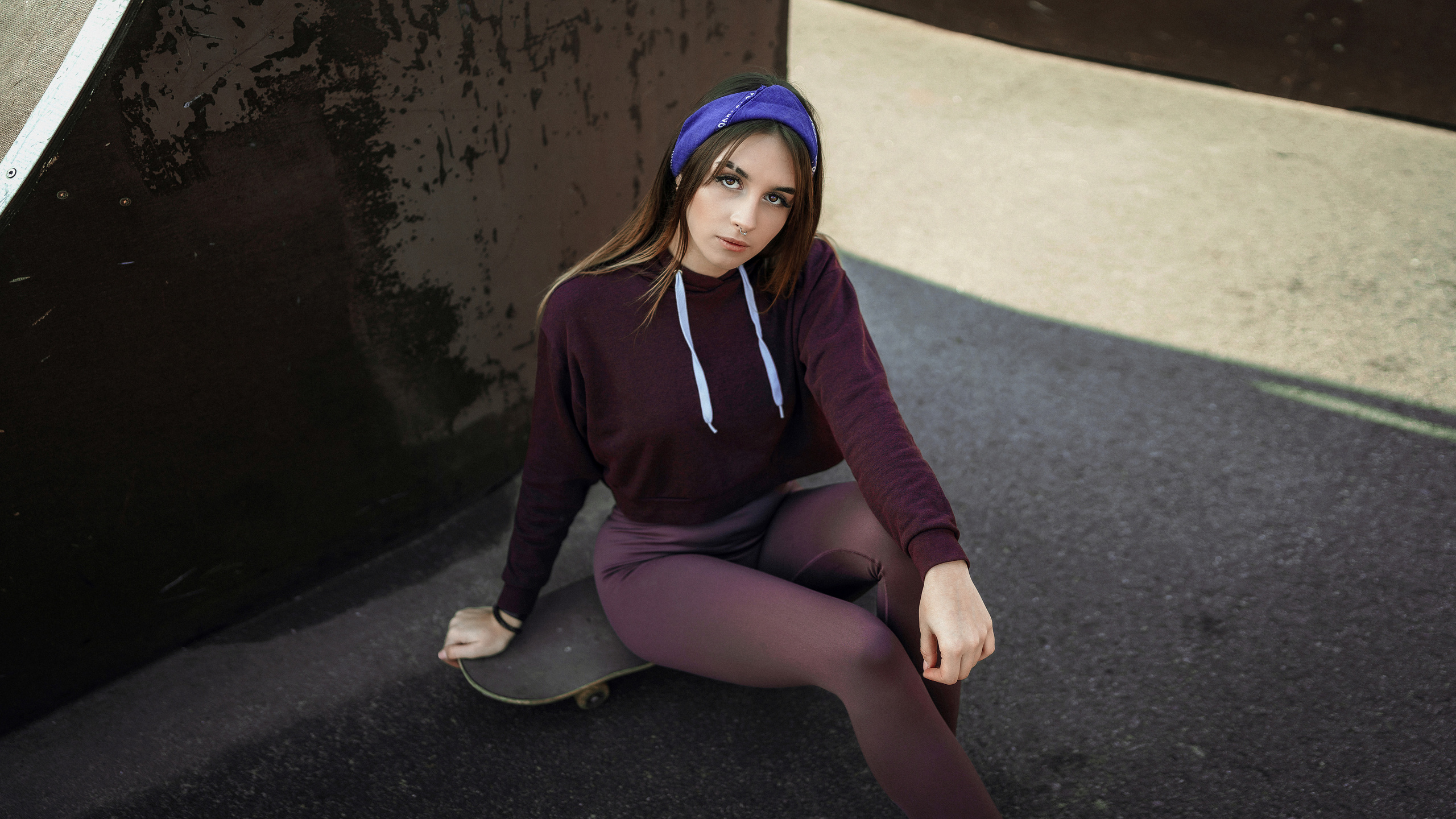 Девочка в спортивном костюме отдыхает в тени сидя на скейте. Фотография Романа Яковенко