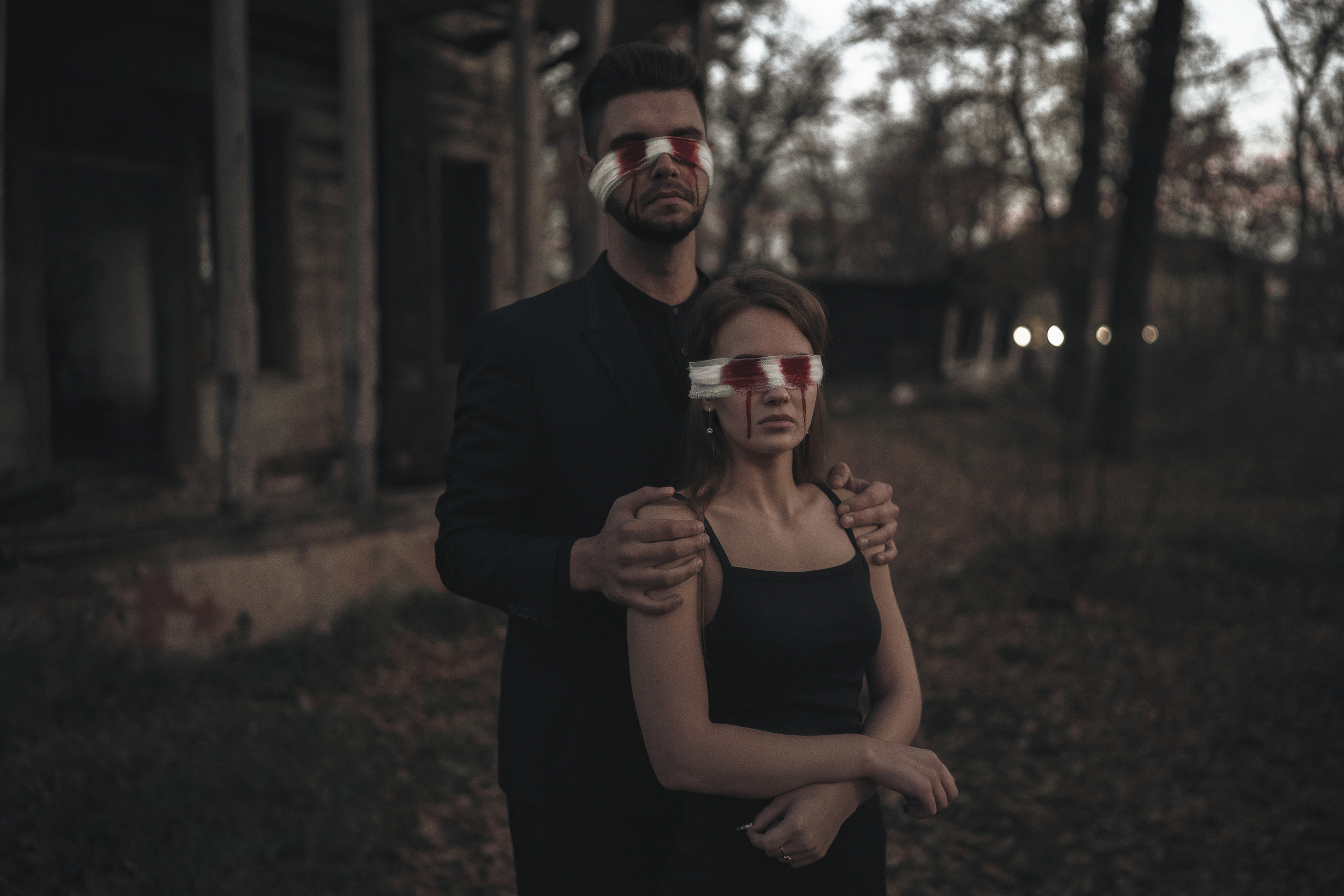 Девушка и парень с повязкой на глазах стоят в обнимку и смотрят на камеру