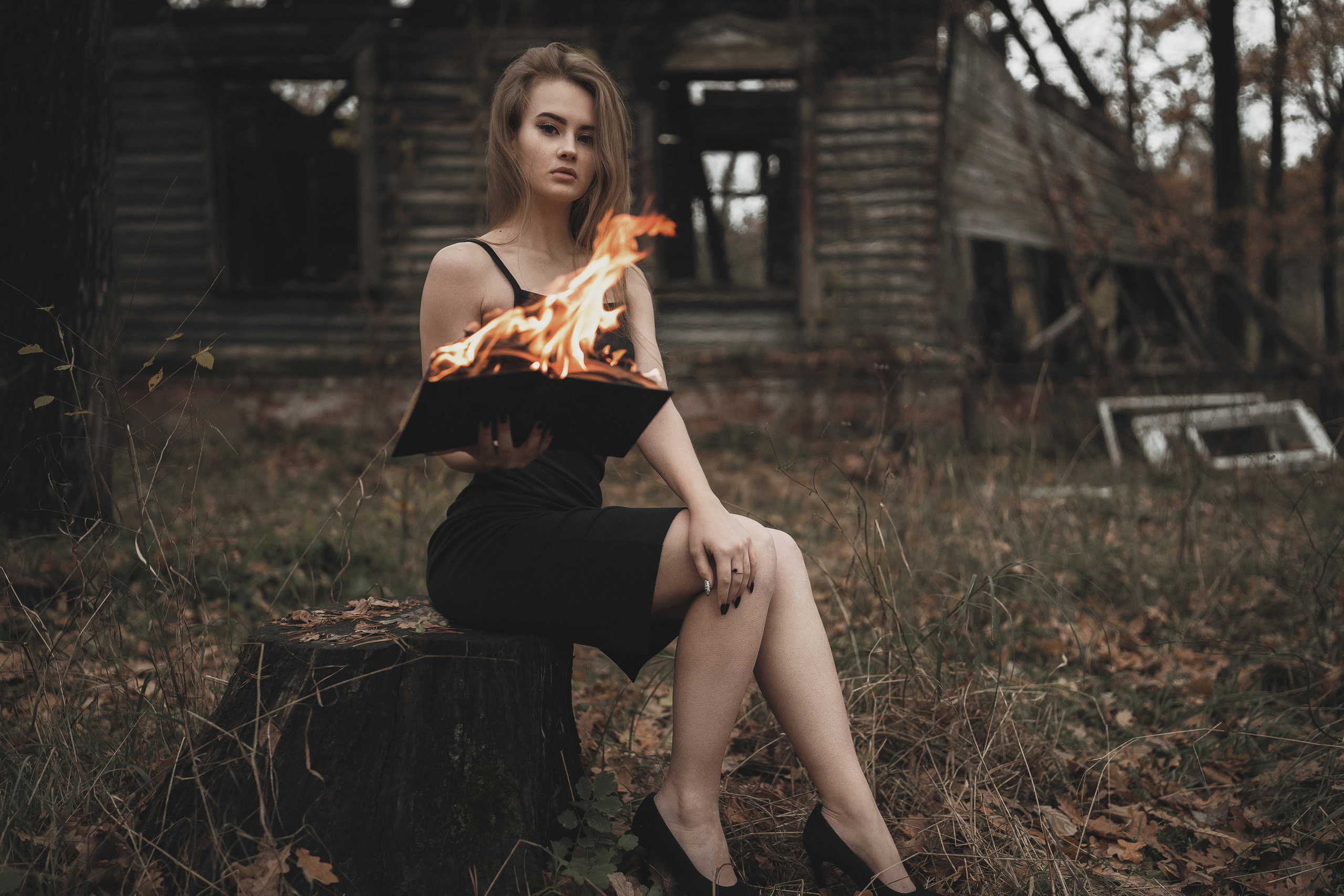 Девушка в черном платье держит горящую книгу