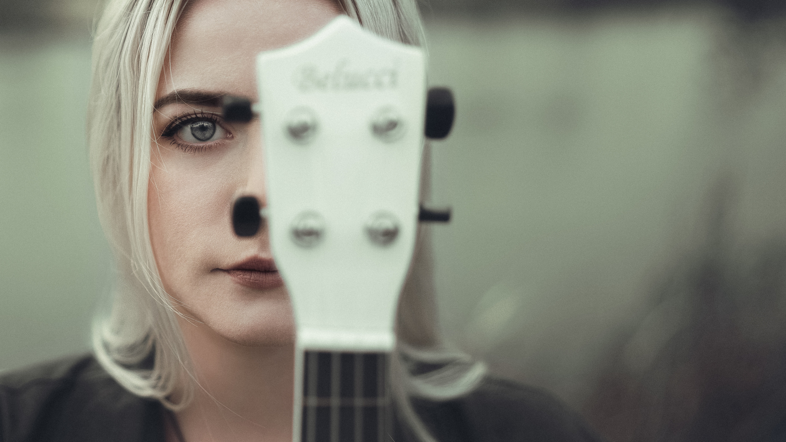 Девочка рукой белую укулеле около лица закрываю половину лица