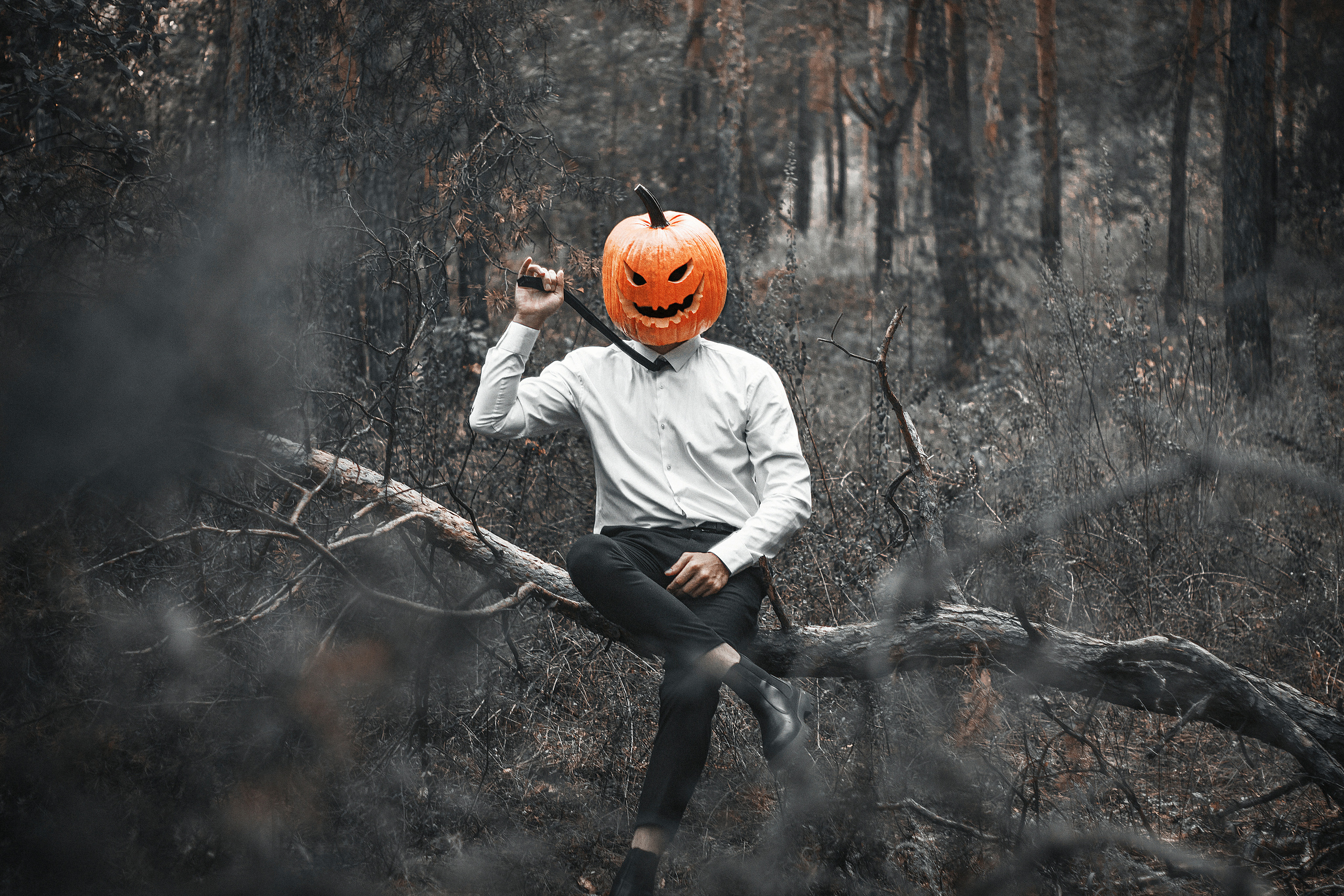 Парень в рубашке в маске тыквы держит галстук