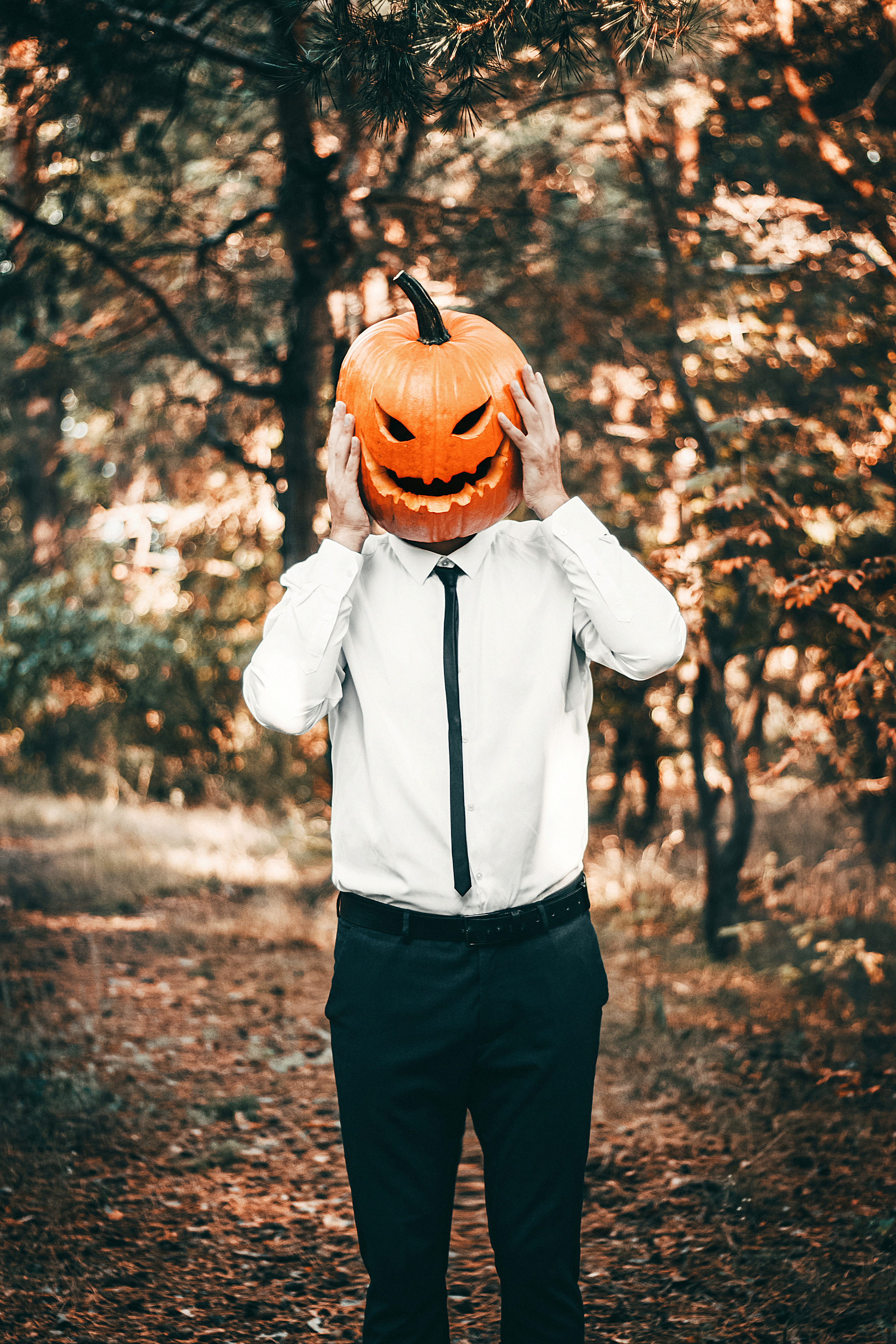 Парень в рубашке держит руками маску тыкву