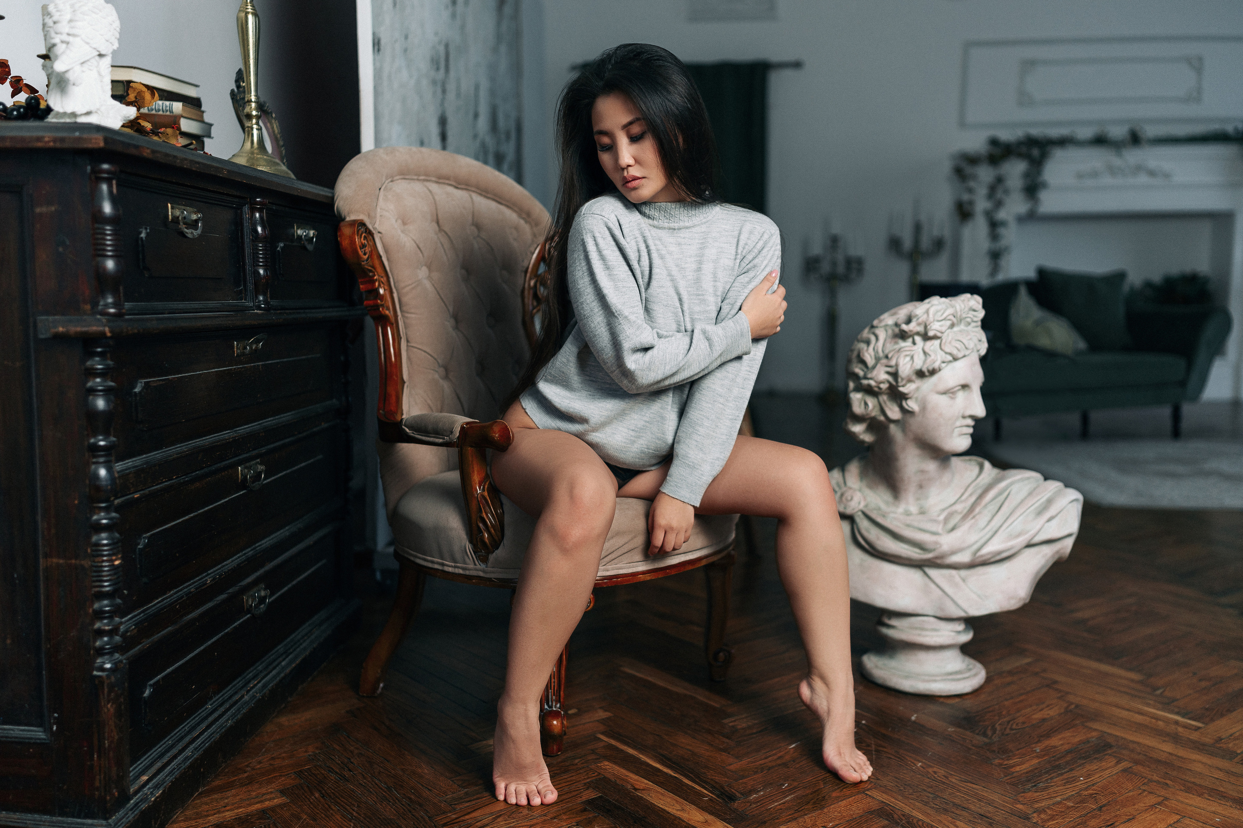 Девушка с азиатской внешностью в серой кофте и черных трусиках сидит в кресле. Фотограф Роман Яковенко