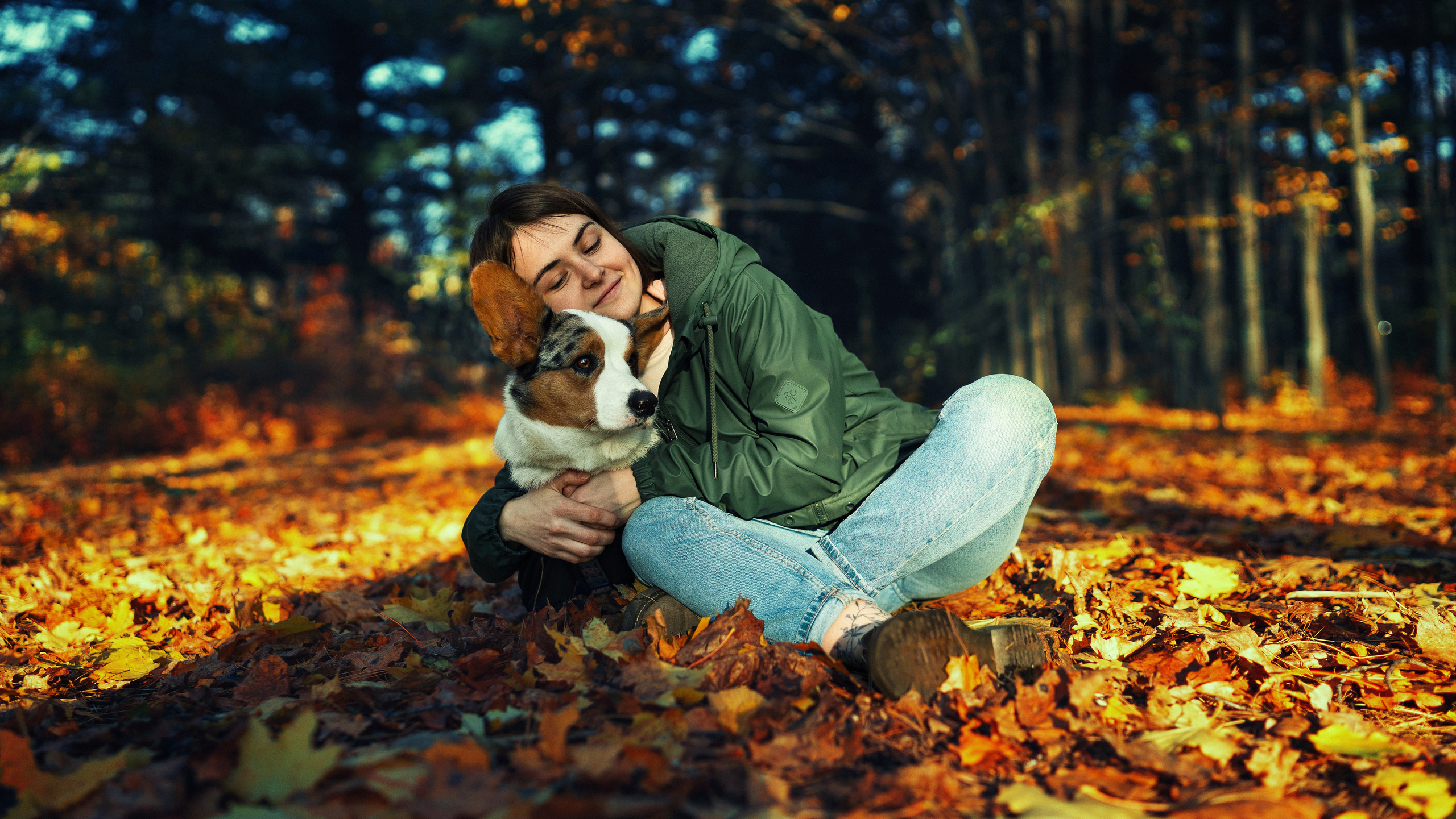 Девочка обнимает собаку породы корги в осеннем парке 