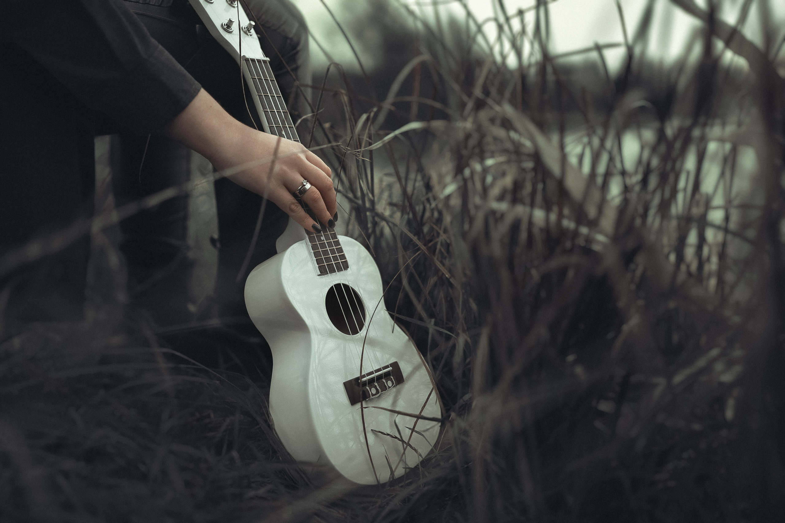 Девочка рукой берет белую укулеле