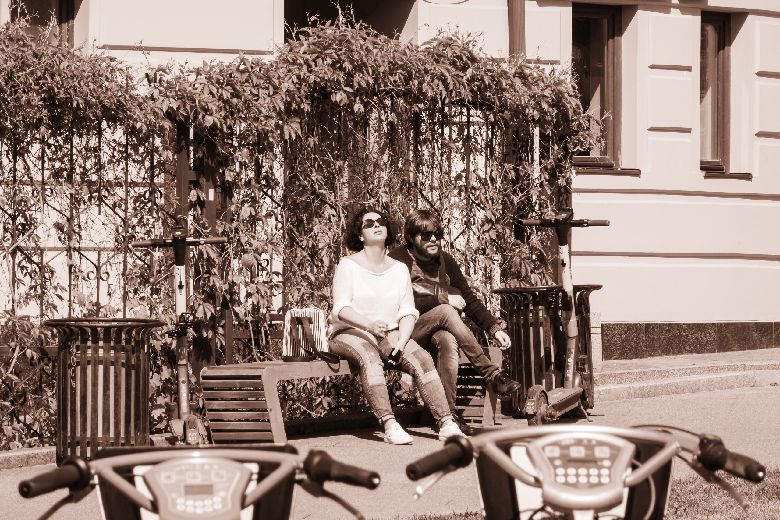 Двое сидят на лавочке и греются под весенним солнцем