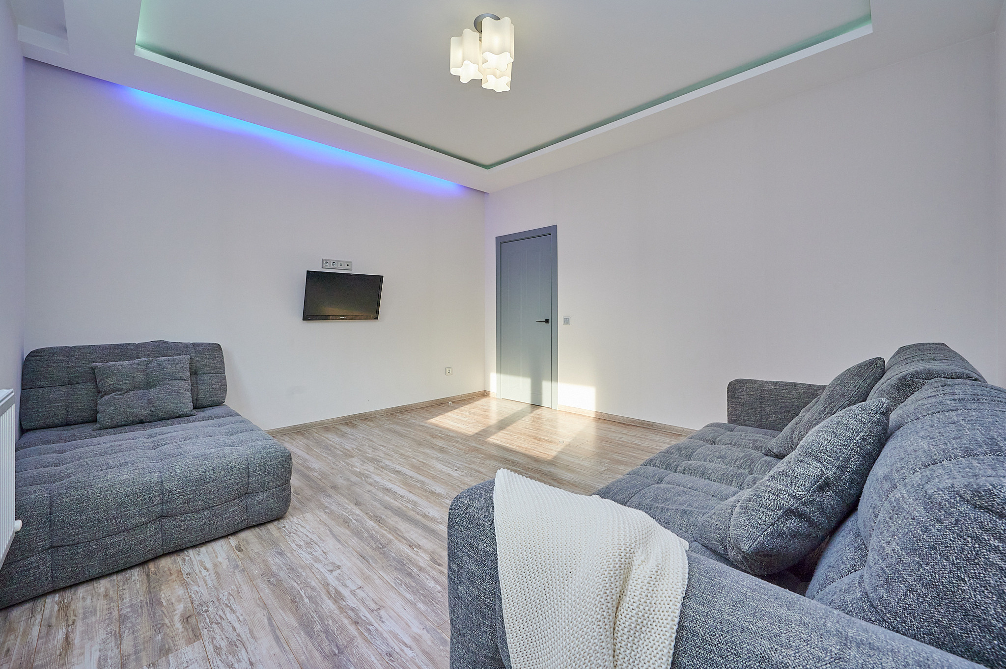 гостиная серый диван светлый ламинат белые обои 