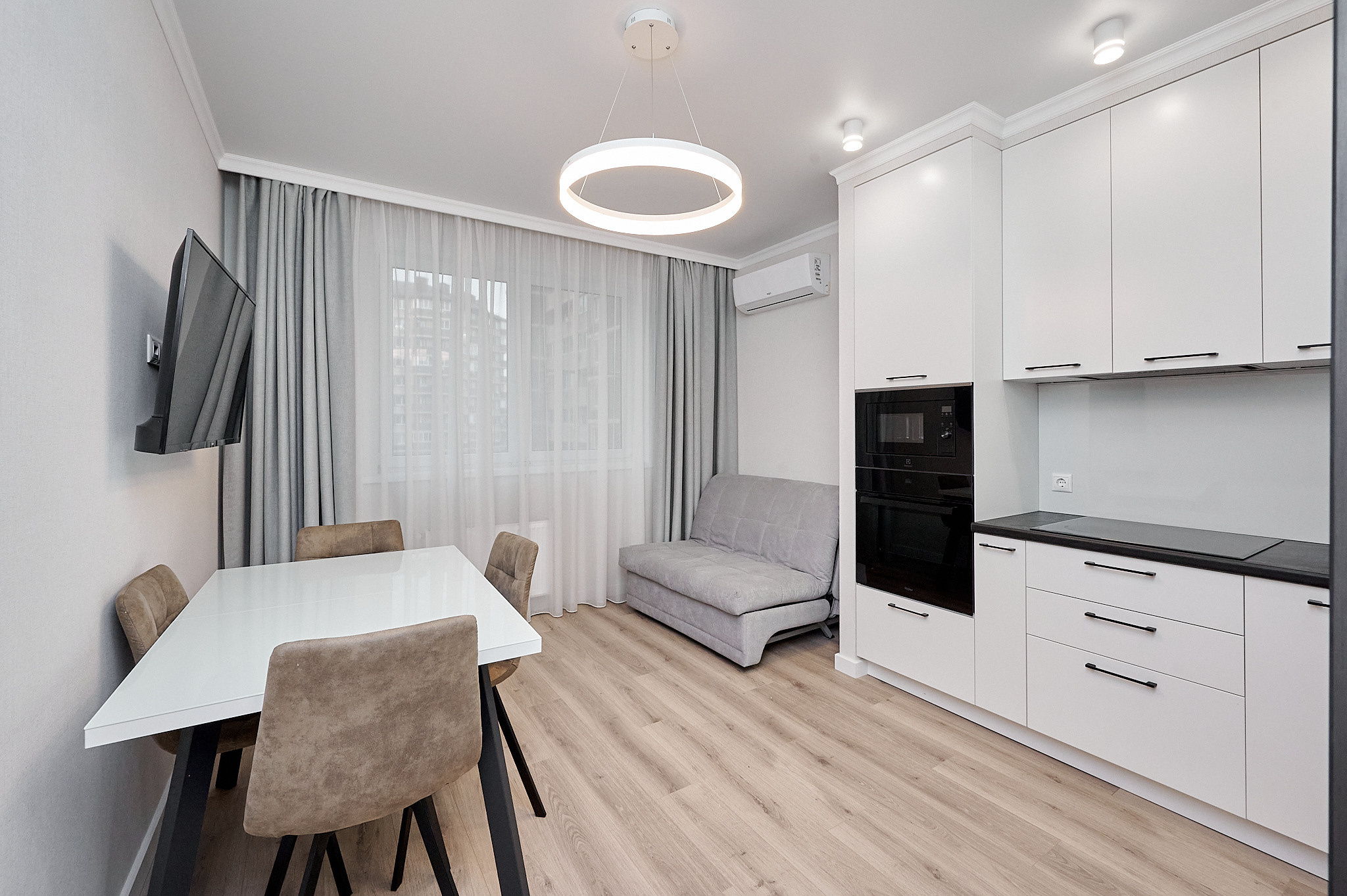 кухня в белой расцветке белые шкафчики белый кухонный стол коричневый стул серый диван 