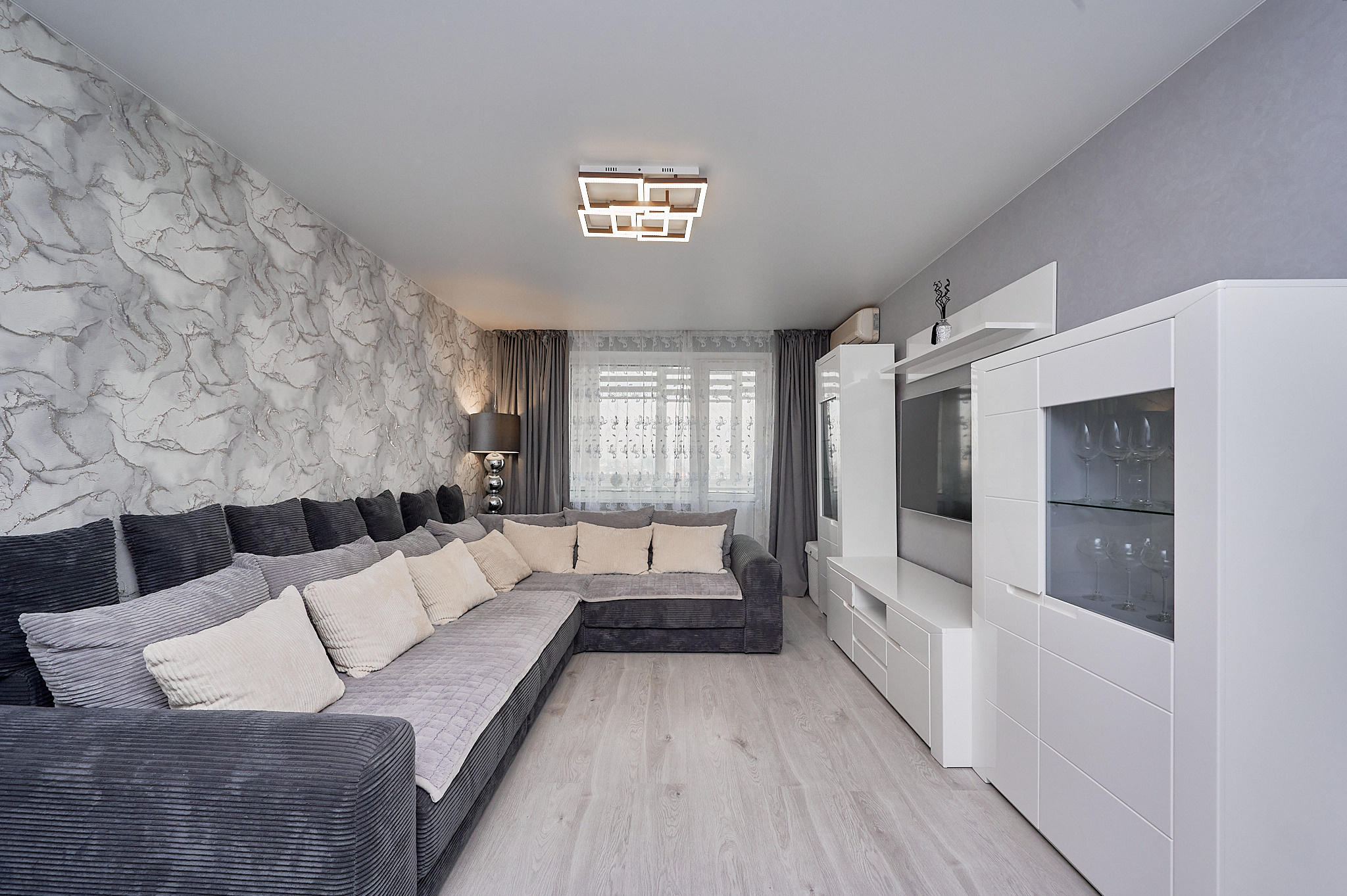 гостиная большой серый диван  белые шкафы 