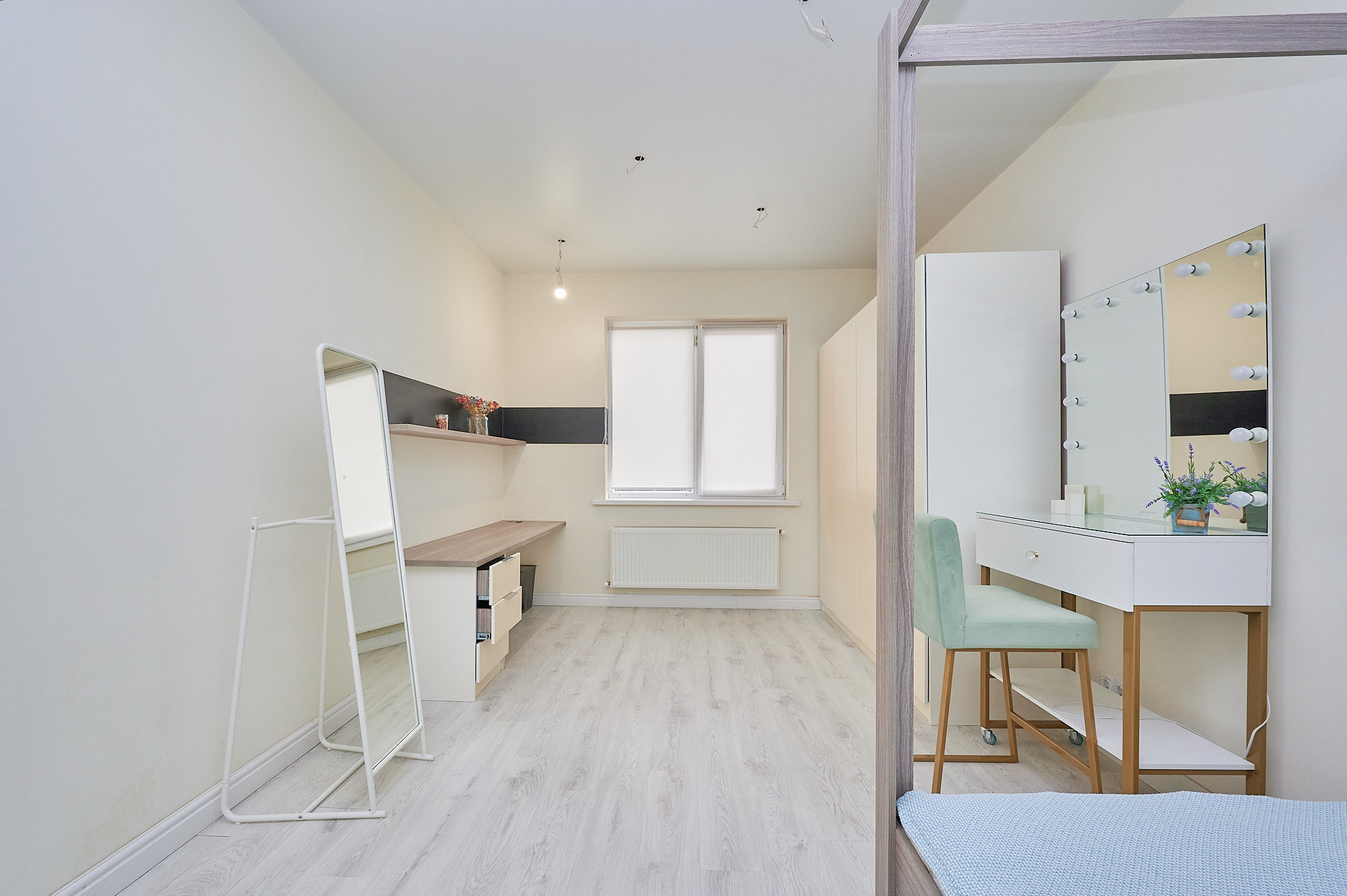 комната белые стены  столик с зеркалом с подсветкой бирюзовый стул  зеркало кровать одноместная 