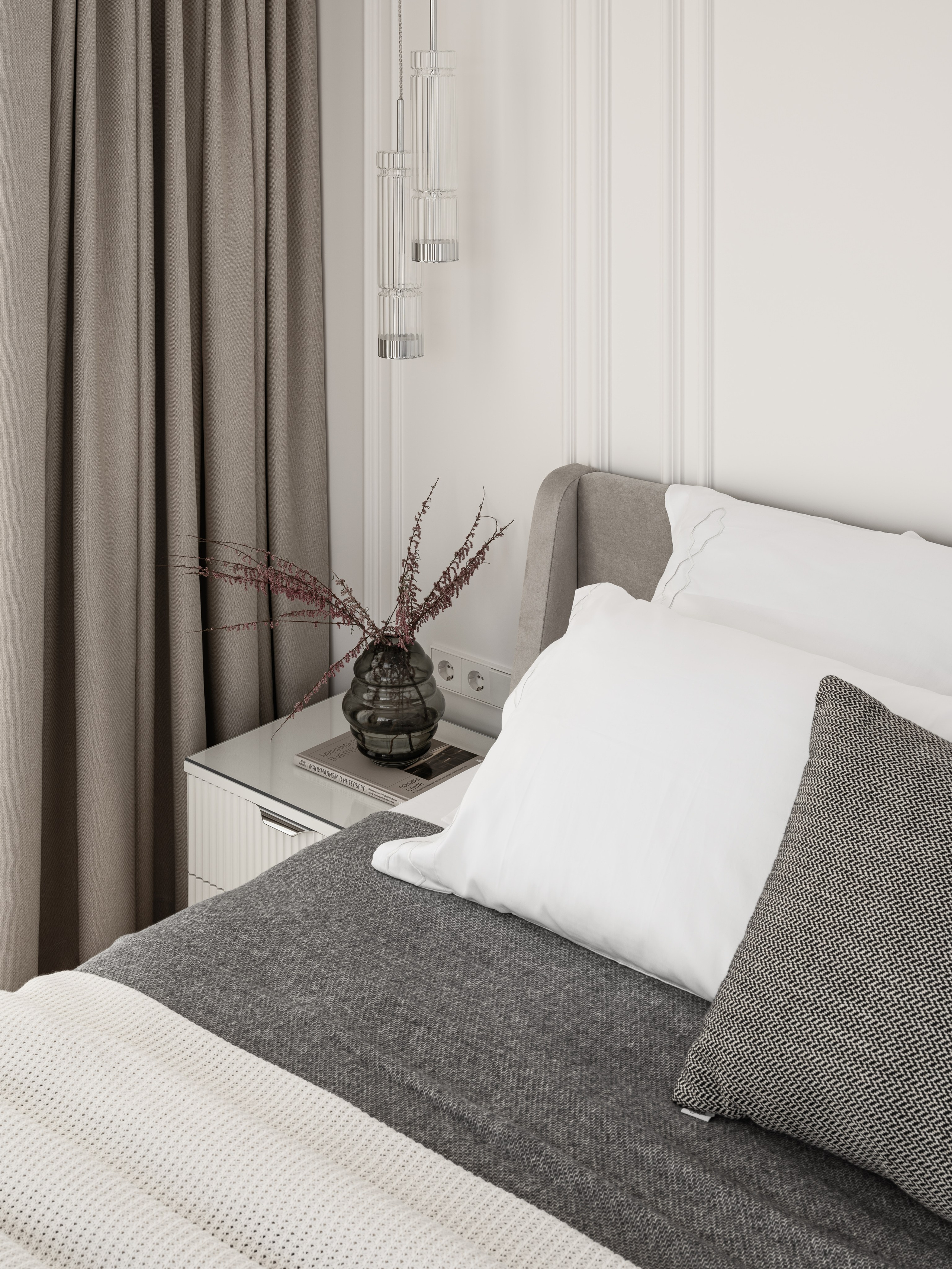 Крупный план кровати в спальне с серым текстилем, белыми подушками и декором на тумбе, лаконичный и уютный интерьер в современном стиле — проект Алёны Боярской, стилист Наталья Якушева, фото Сергей Денисенко.