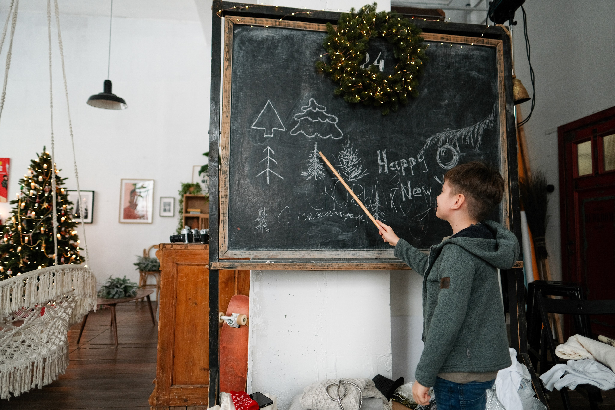 Мальчик с указкой у доски с новогодней тематикой.