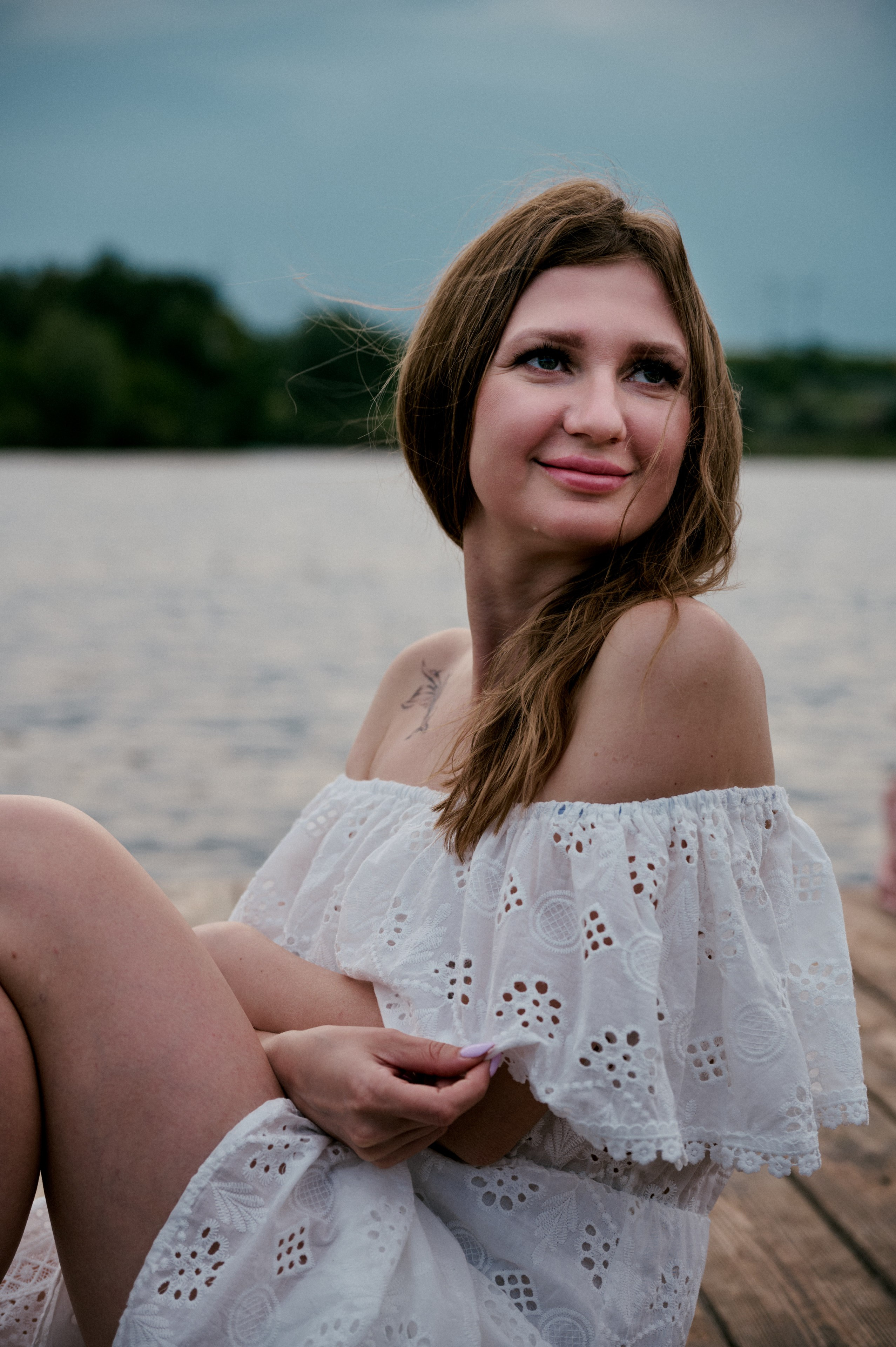  Крупный портрет Евгении у озера, она смотрит в сторону с лёгкой улыбкой.