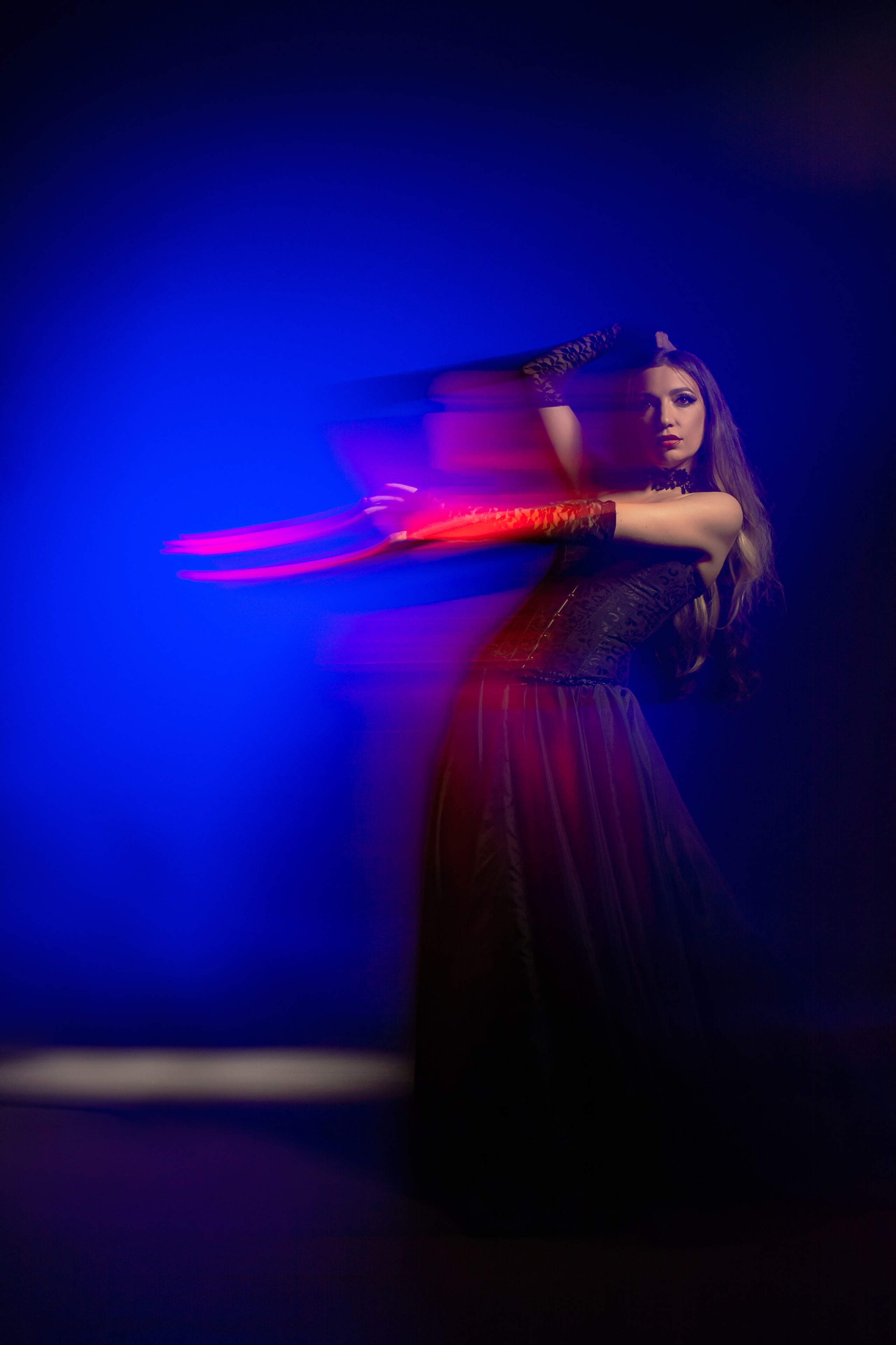 Вихрь цветов и света: фото в стиле смешанного света, где девушка становится художественным полотном, раскрашенным красными, синими, бирюзовыми и розовыми оттенками