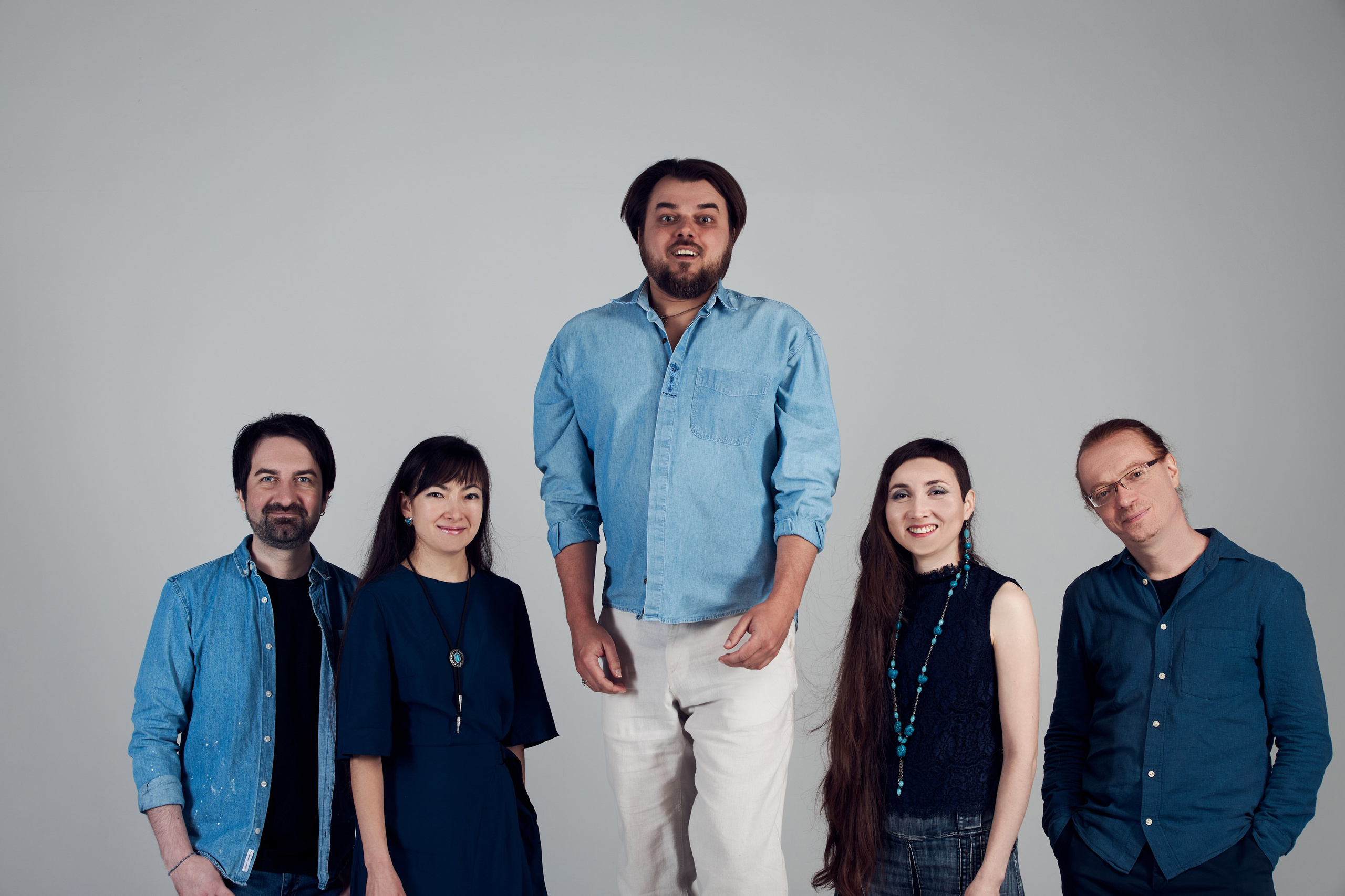 Групповой снимок пяти человек средне дальней крупности на афишу для концерта, где один подпрыгивает а остальные четверо стоят