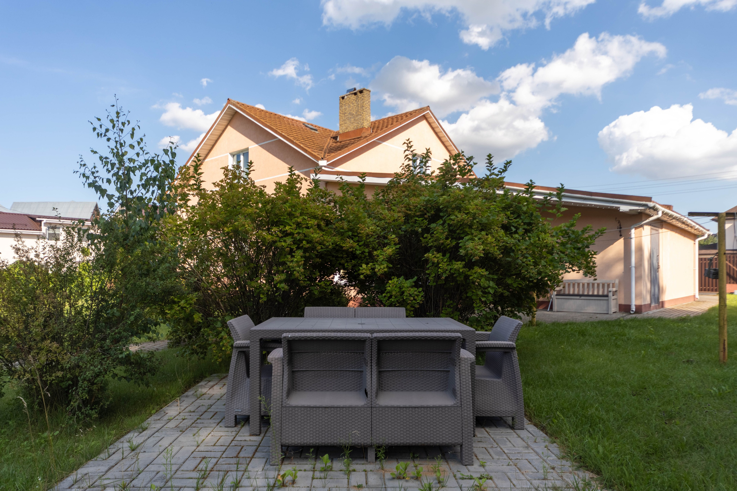 Летний столик со стульями в зеленом дворе усадьбы в Хатежино