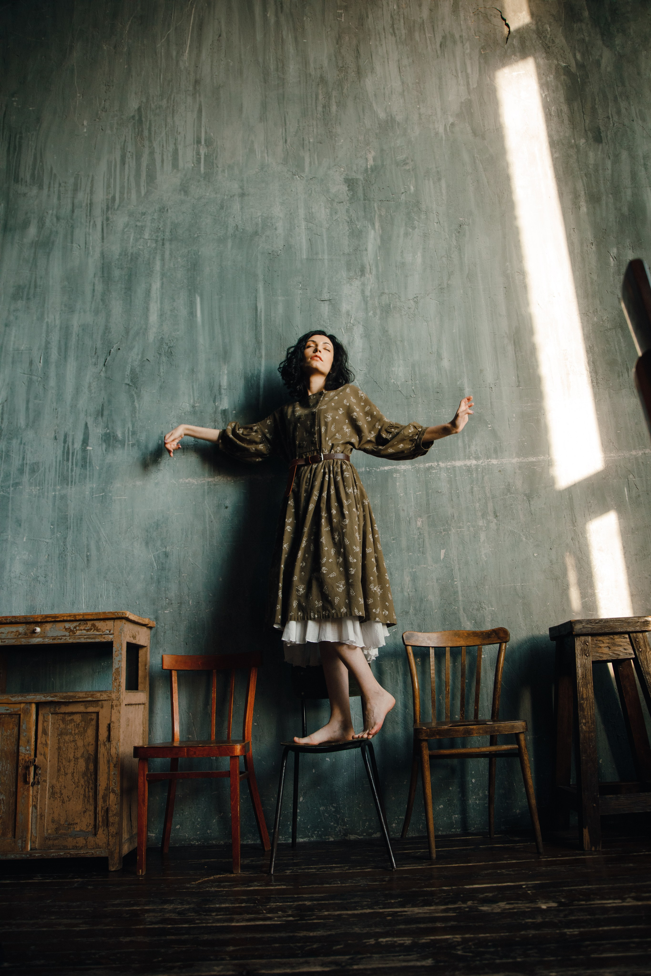 Девушка в платье позирует во весь рост для художественного портрета.