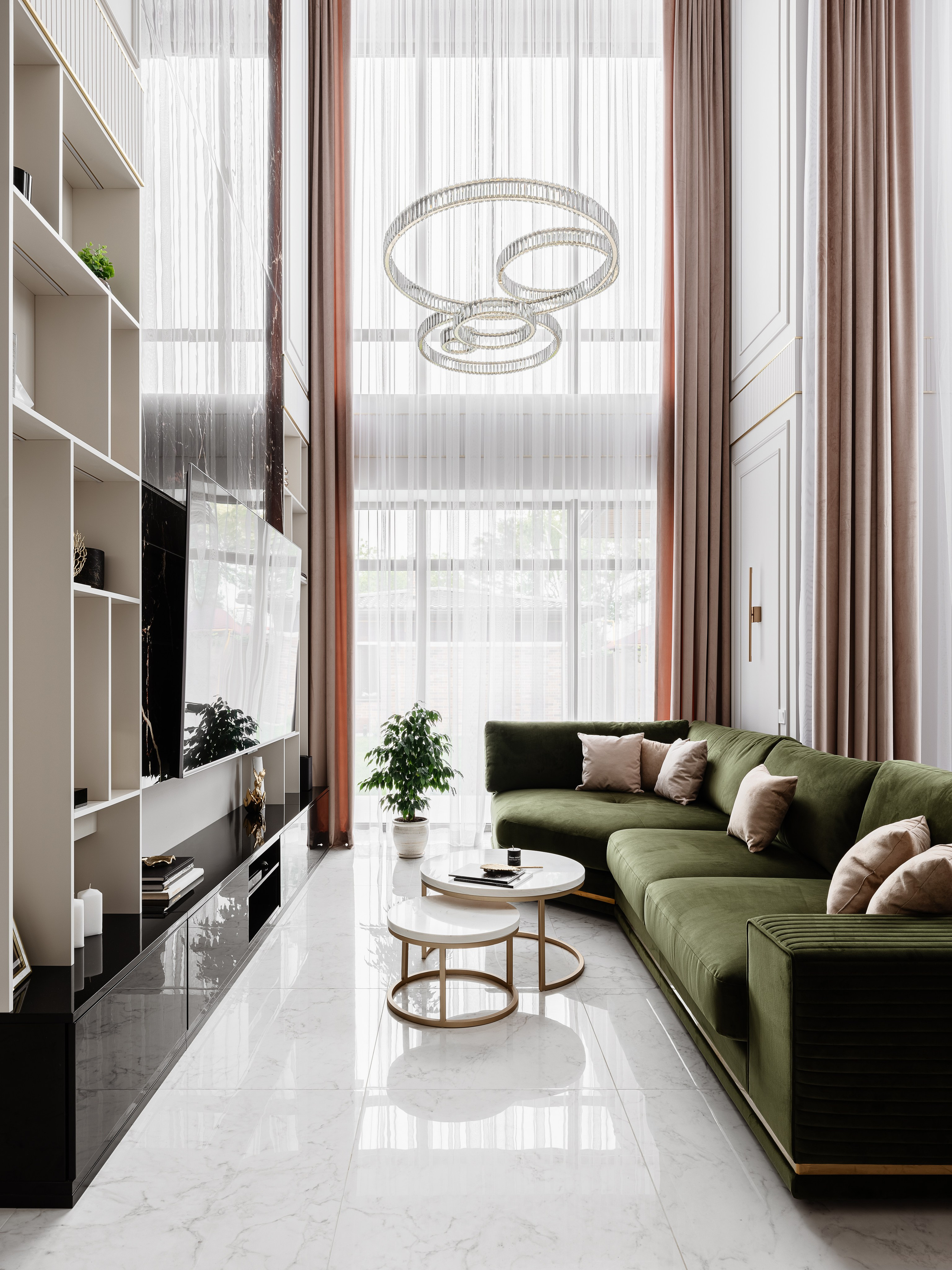Общий вид гостиной с высоким потолком, зелёным диваном и подвесной люстрой из стеклянных колец, мраморный пол и светлые шторы подчеркивают роскошь интерьера, дизайнер Евгения Ермошина, фото Сергея Денисенко.
