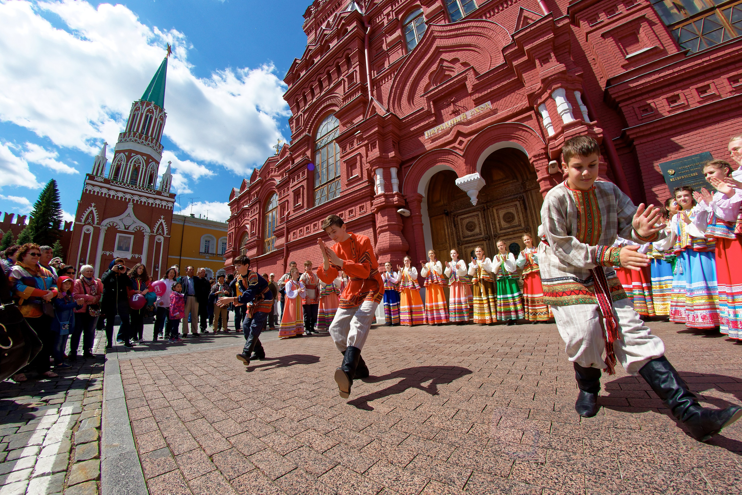 Народные танцы на улице перед Историческим музеем на Красной площади в Москве - дети и подростки в русских народных костюмах, уличное выступление, фотосъемка городских мероприятий