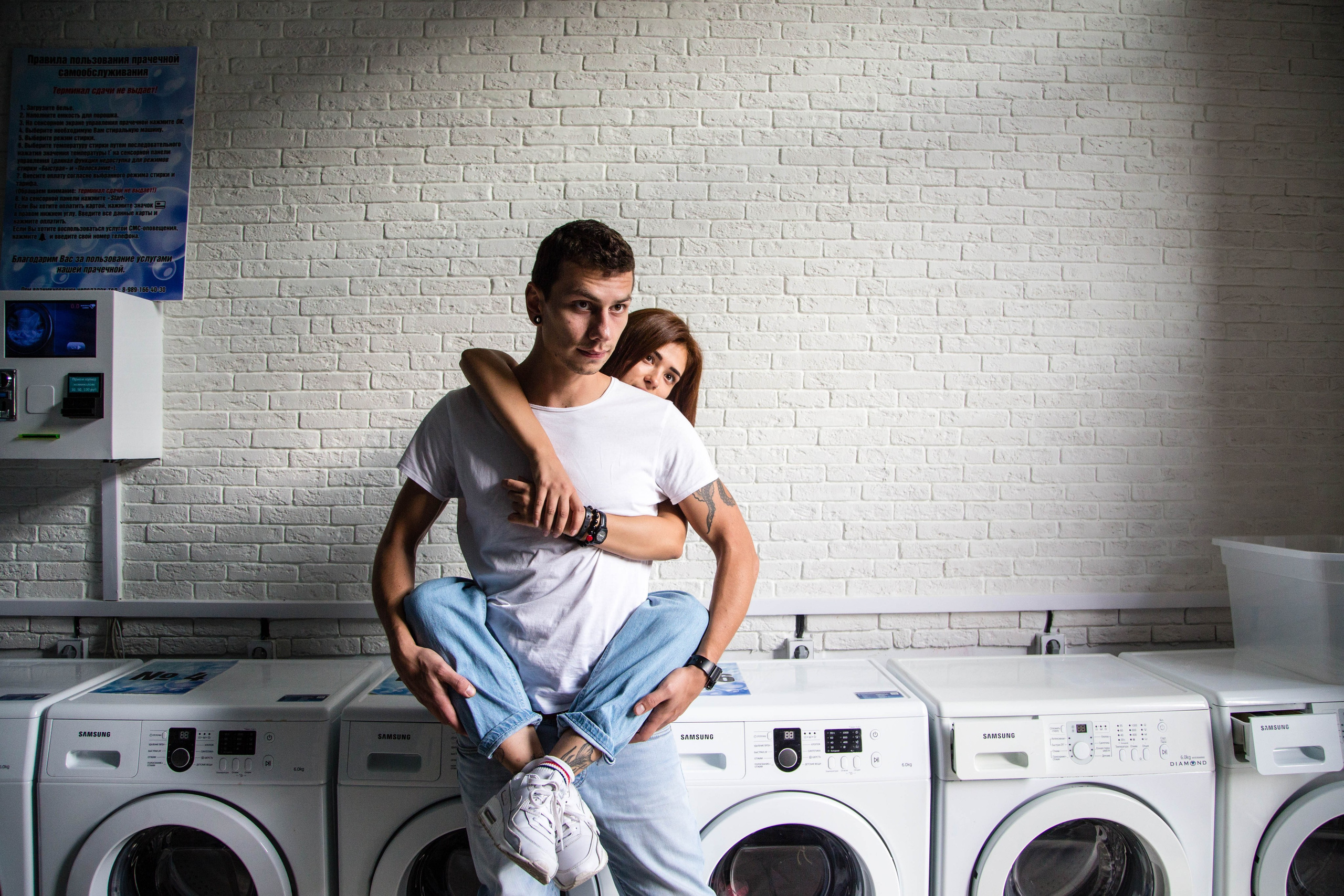 Девушка обнимает парня с сзади внутри прачечной