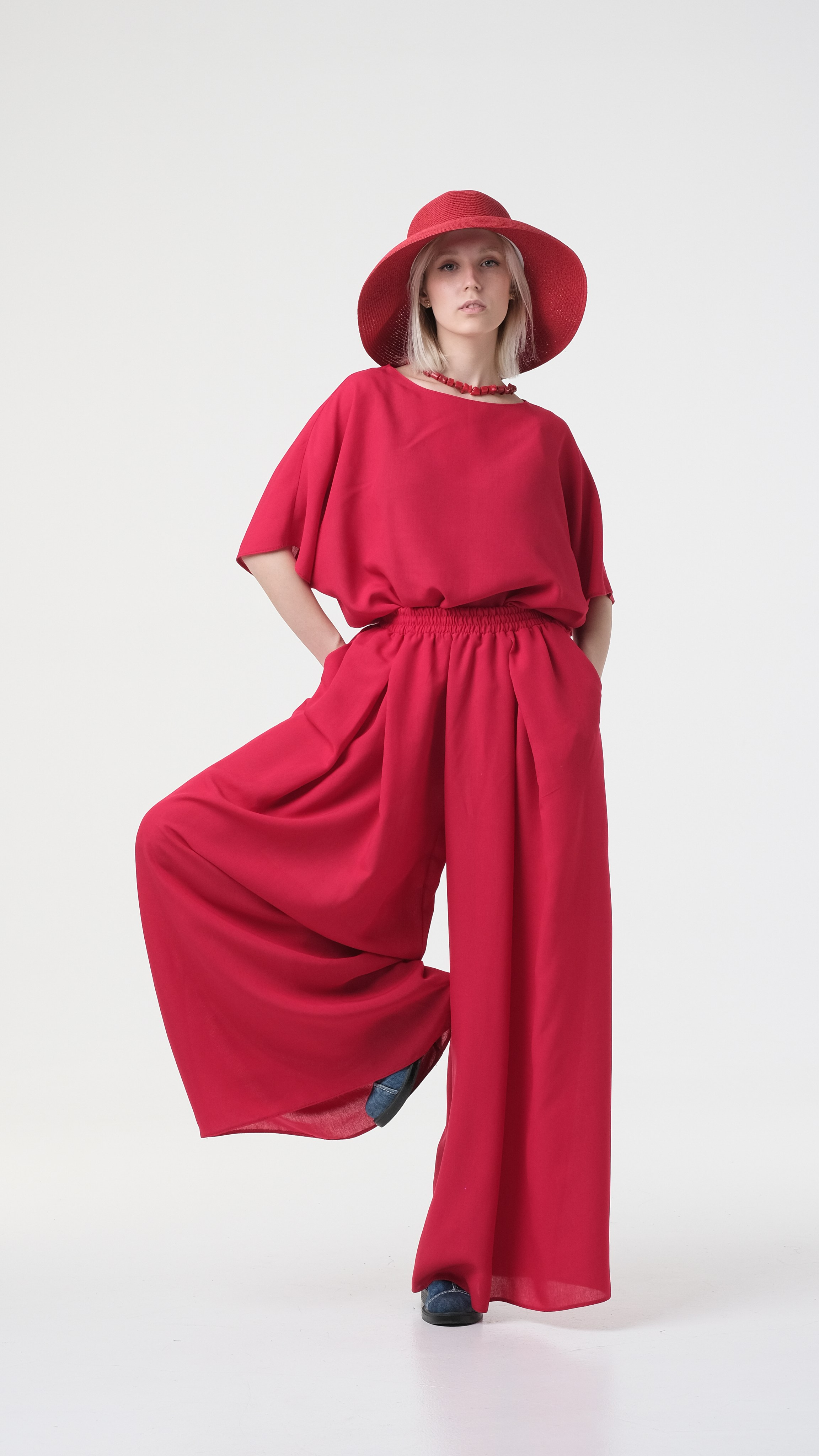 Женщина в красном. Стильный красный костюм в сочетании с красной шляпой. Красивое позирование на циклораме.