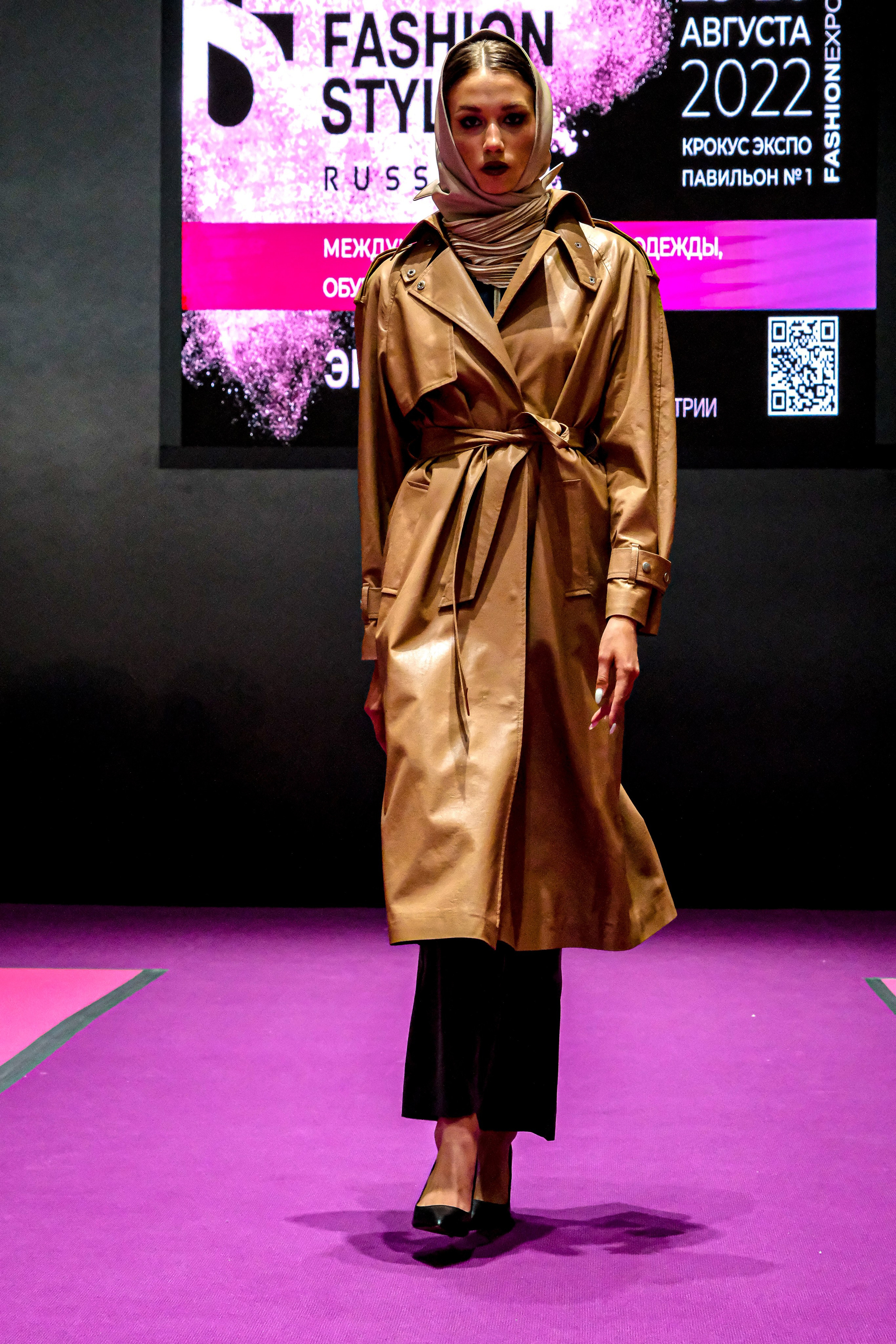  "Модели в ярких нарядах проходят по подиуму во время показа мод, освещенные яркими софитами и окруженные восторженными зрителями."