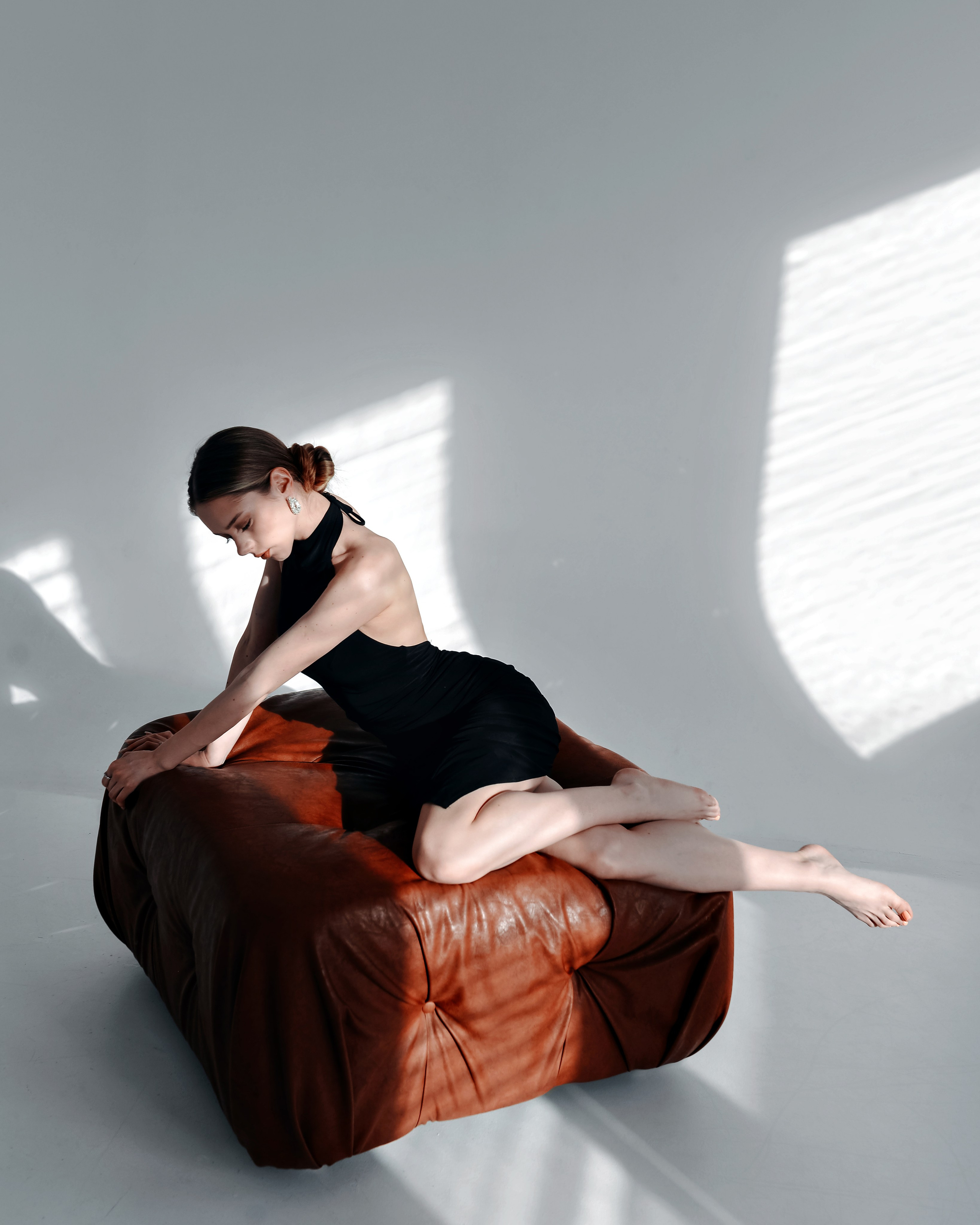 Девушка позирует в минималистичной студии с акцентом на линиях тела