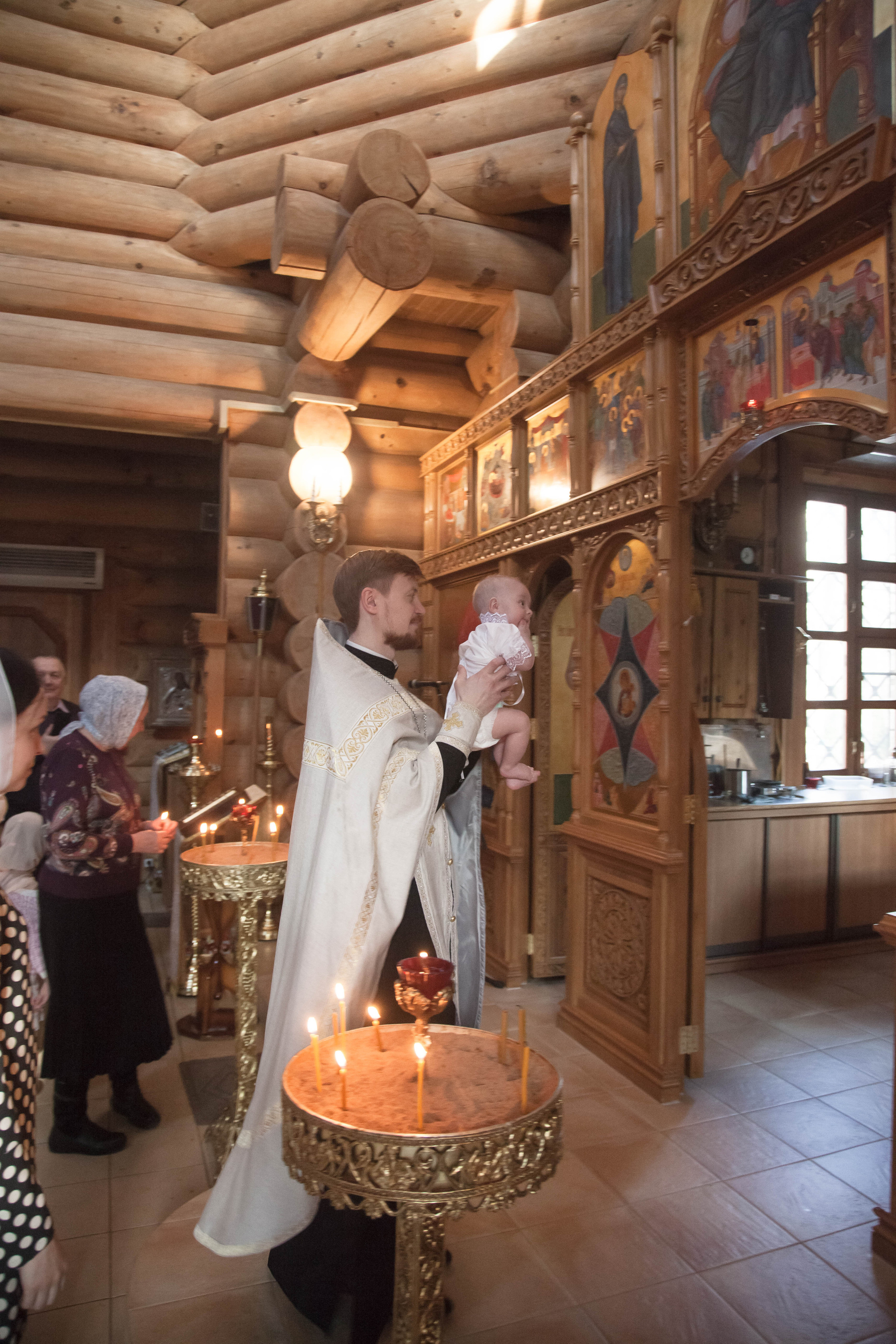 Священик исполняет обряд таинства крещения.