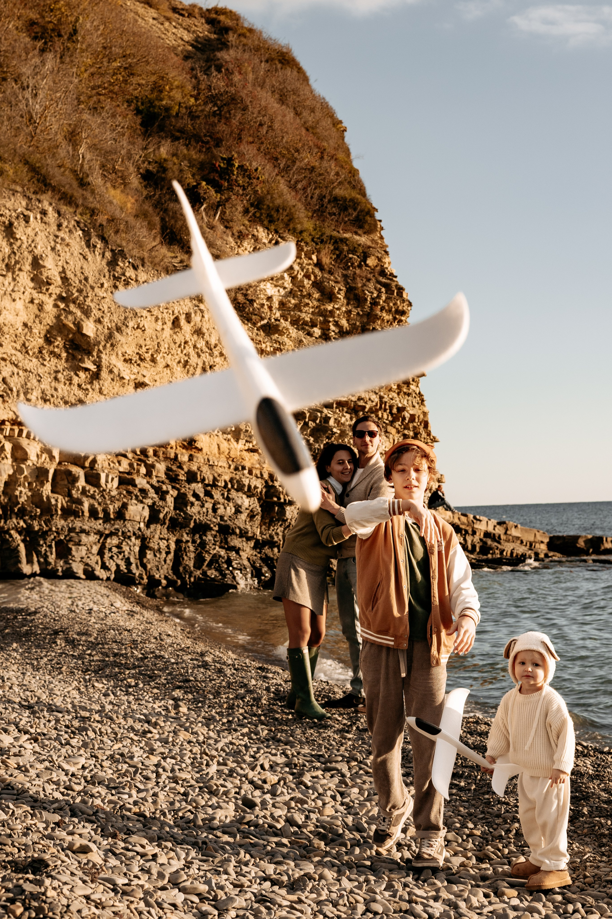 Сын смеется, пытаясь поймать свой бумажный самолетик