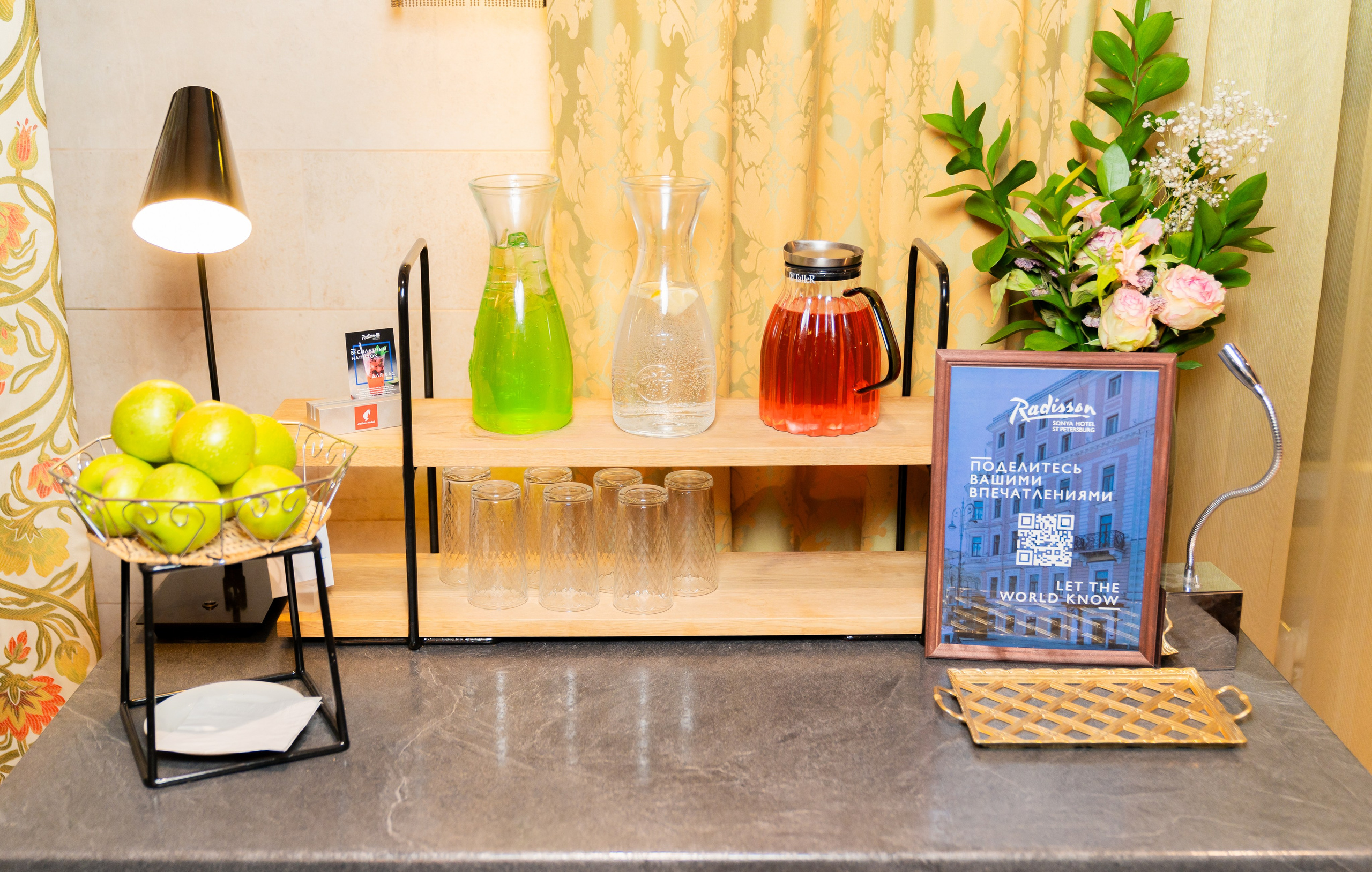 Стол с напитками, фруктами и QR-кодом для отзывов гостей. Фото Евгения Мальцева в Radisson Sonya Hotel.