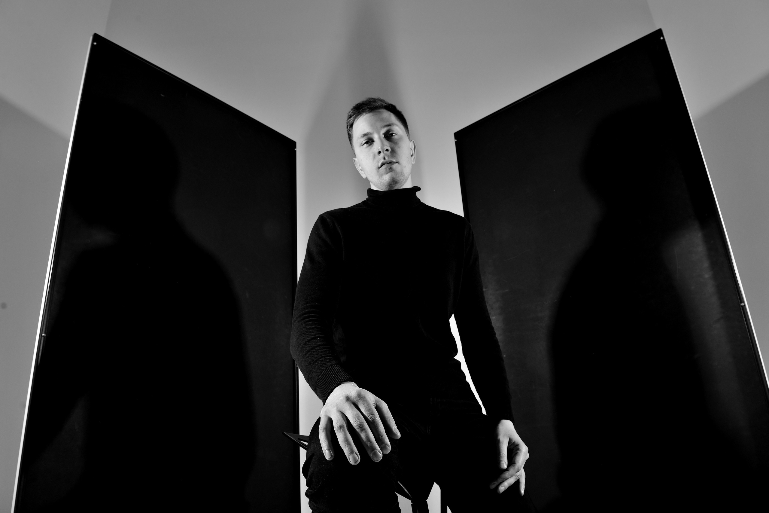 Портретная фотография мужчины в черном на фоне черных отражателей в фотостудии.