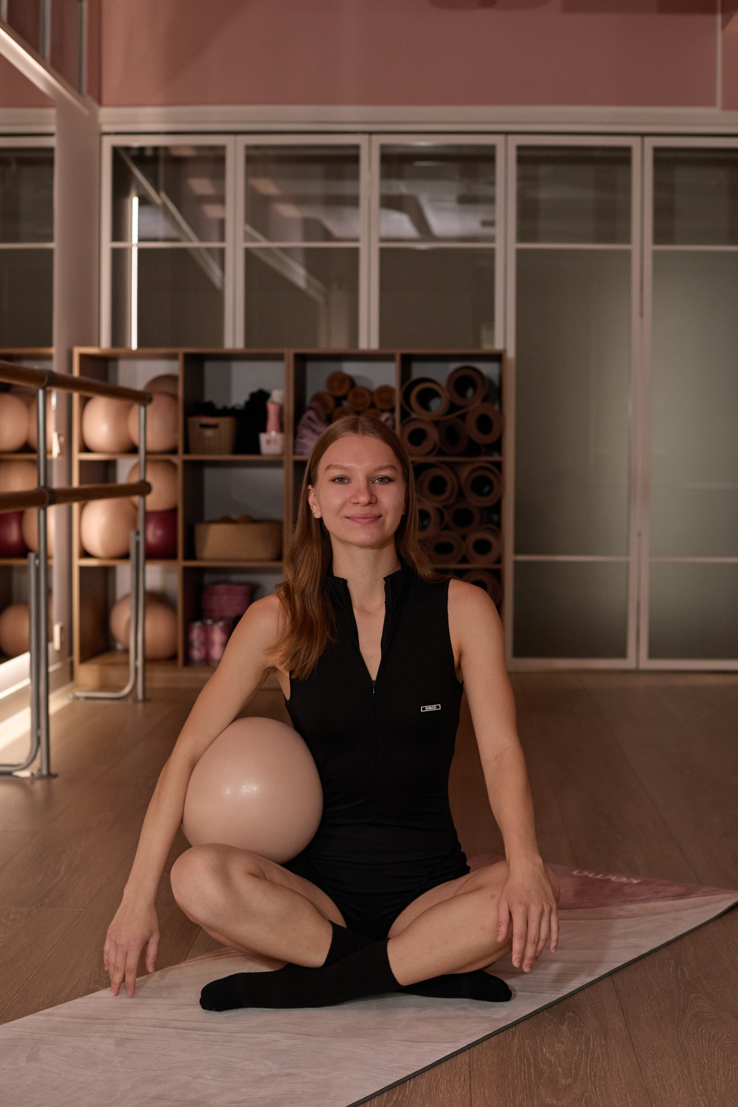 фитнес-тренер в зале у зеркала сидит с мячом