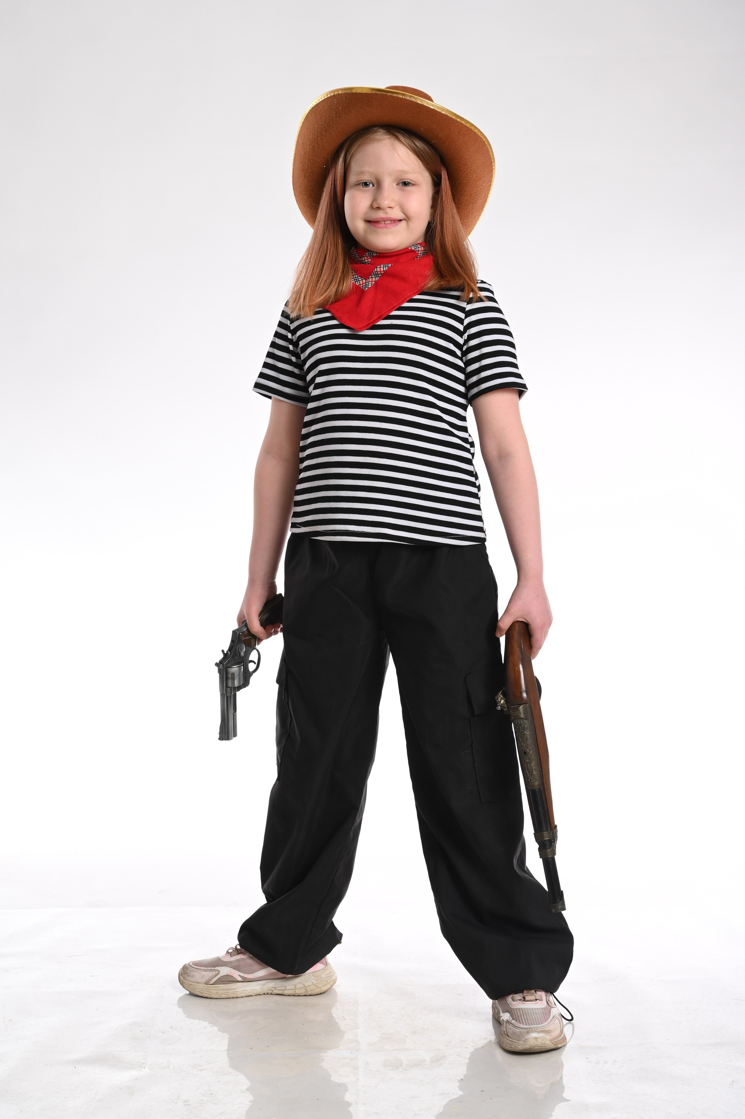 Девочка в костюме ковбоя держит биту в фотостудии