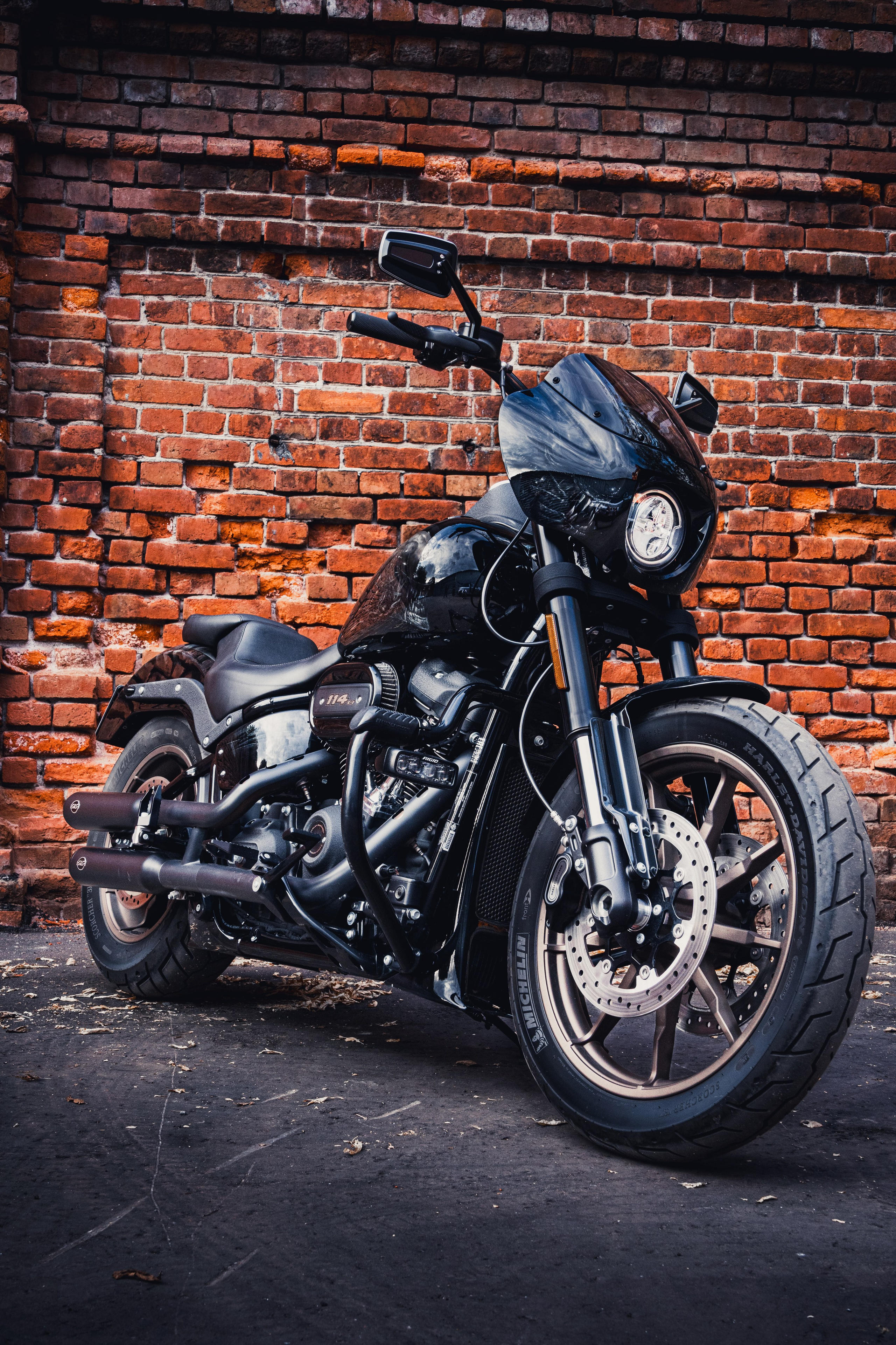 Стильный чёрный Harley-Davidson с тёмной аэрографией, съёмка у кирпичной стены