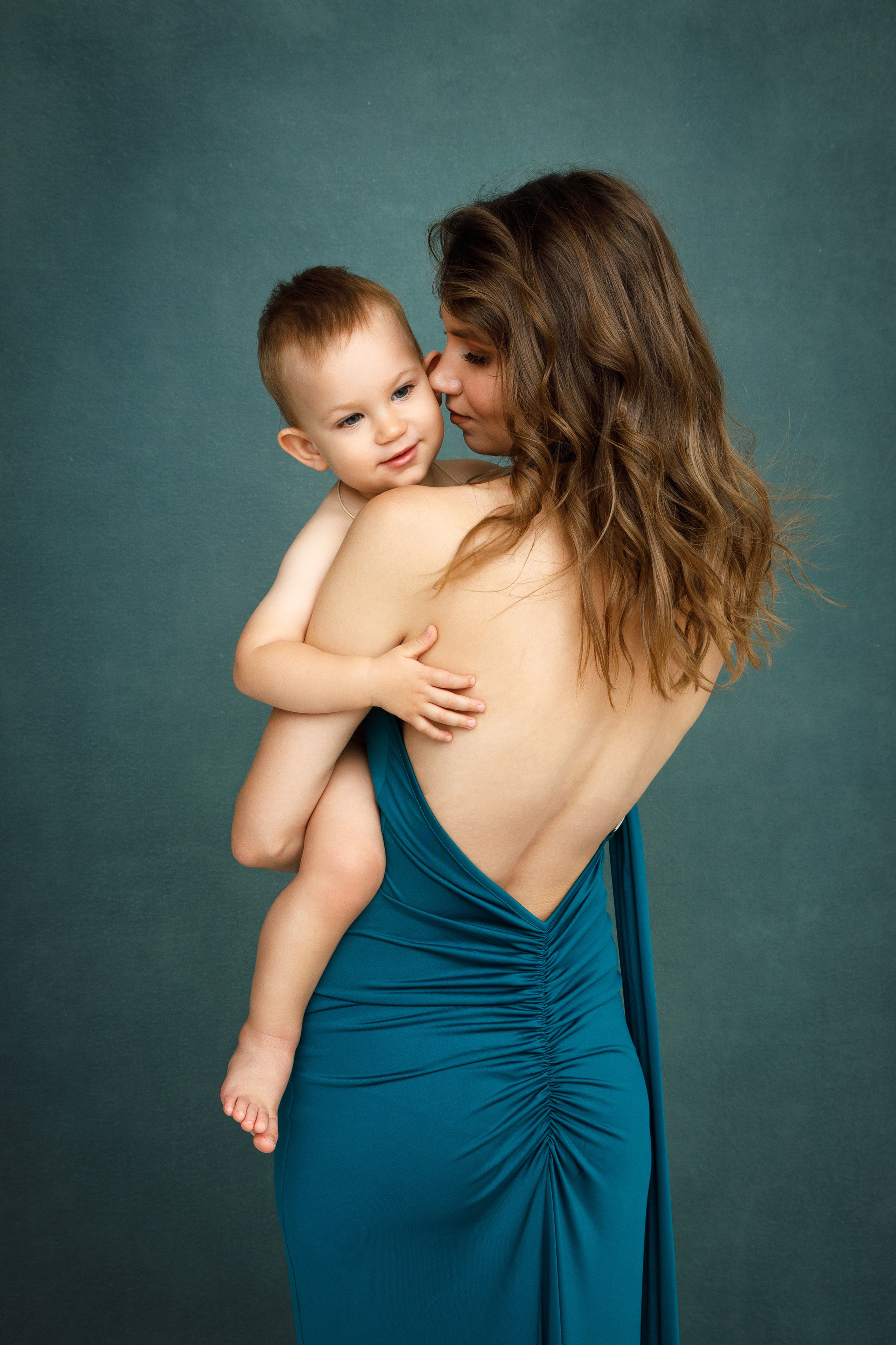 Мама стоит спиной и держит на руках маленького голого ребенка