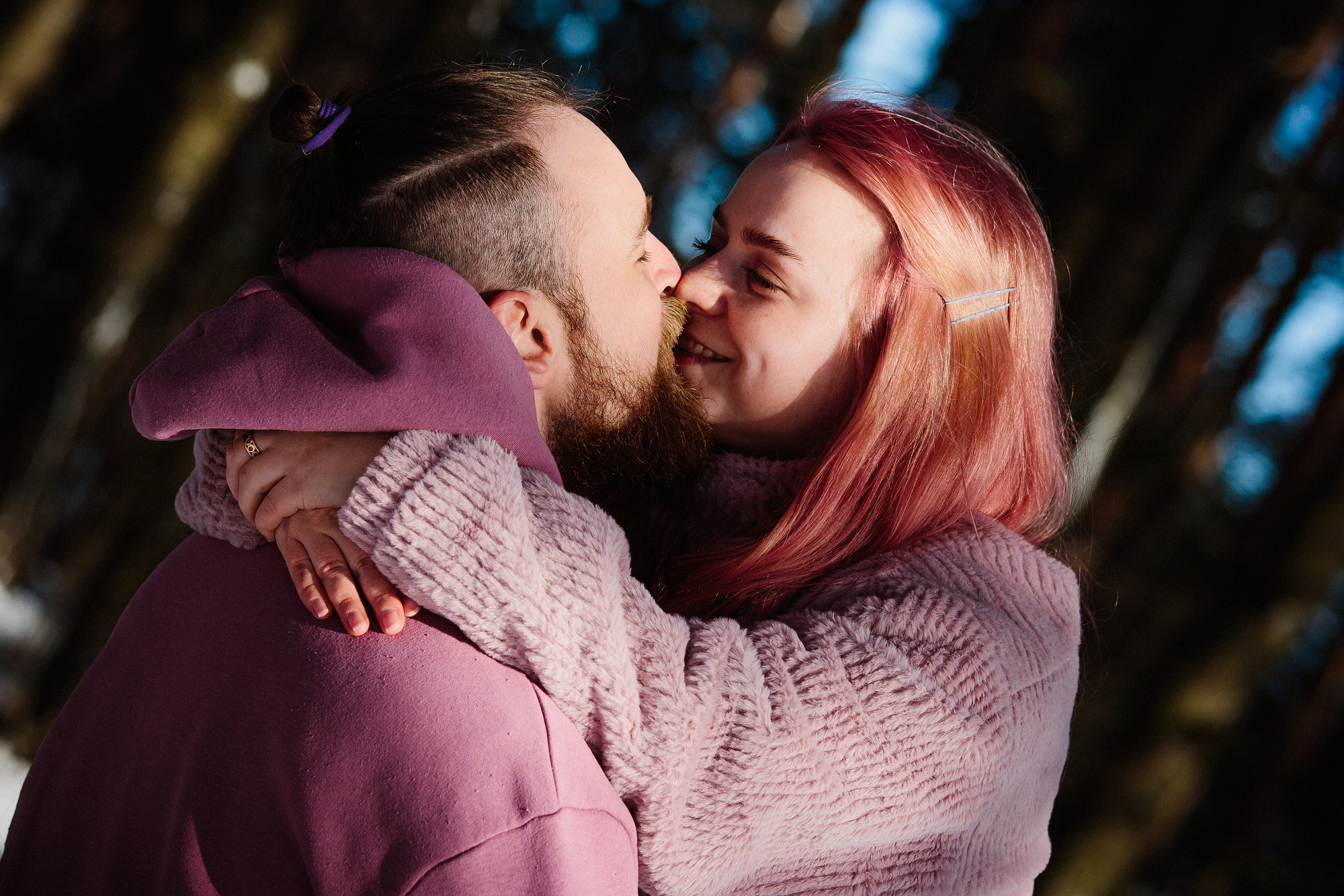 Молодые люди обнимаются в лесу на солнце зимой