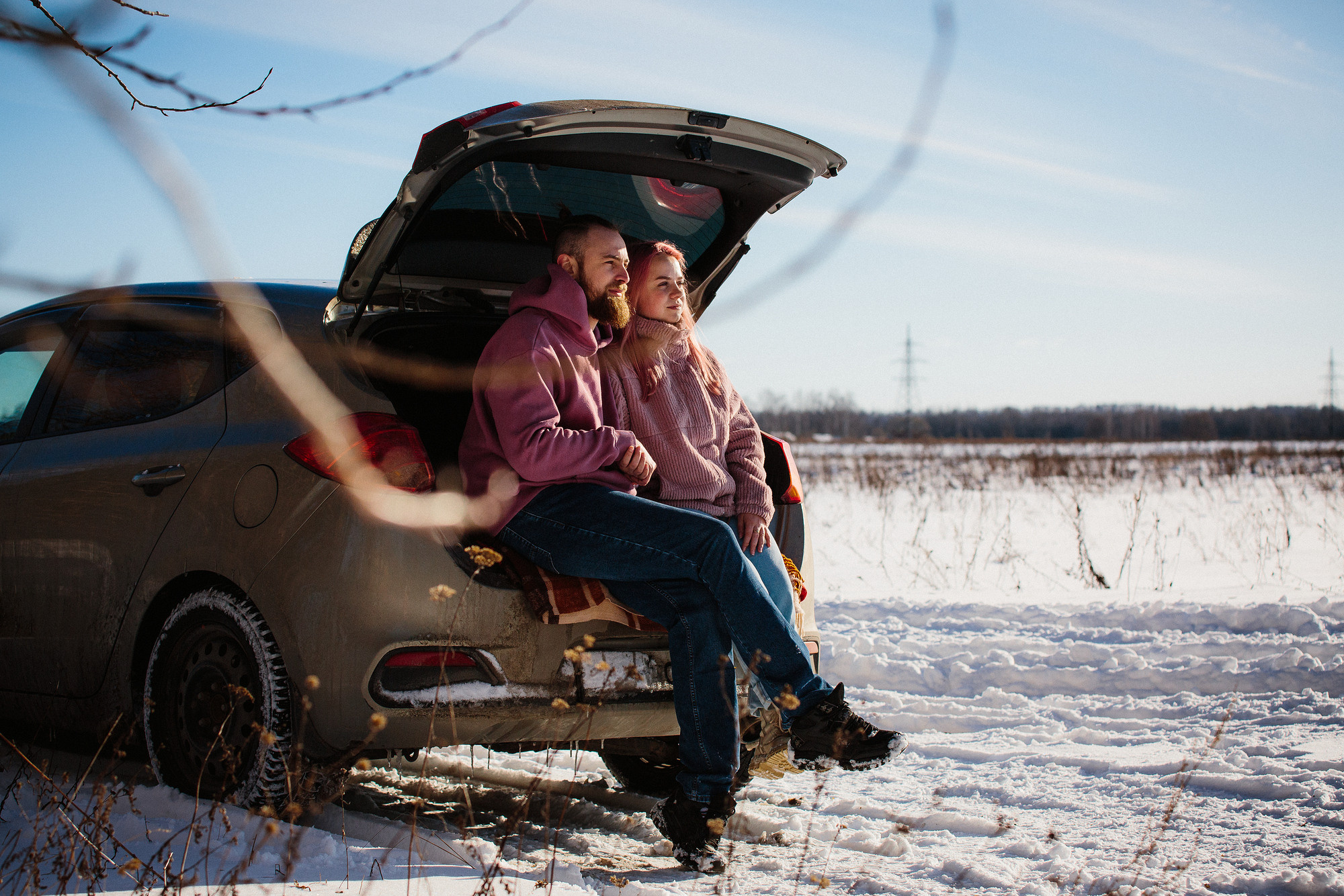 Пара на пикнике в багажнике своей машины зимой возле леса