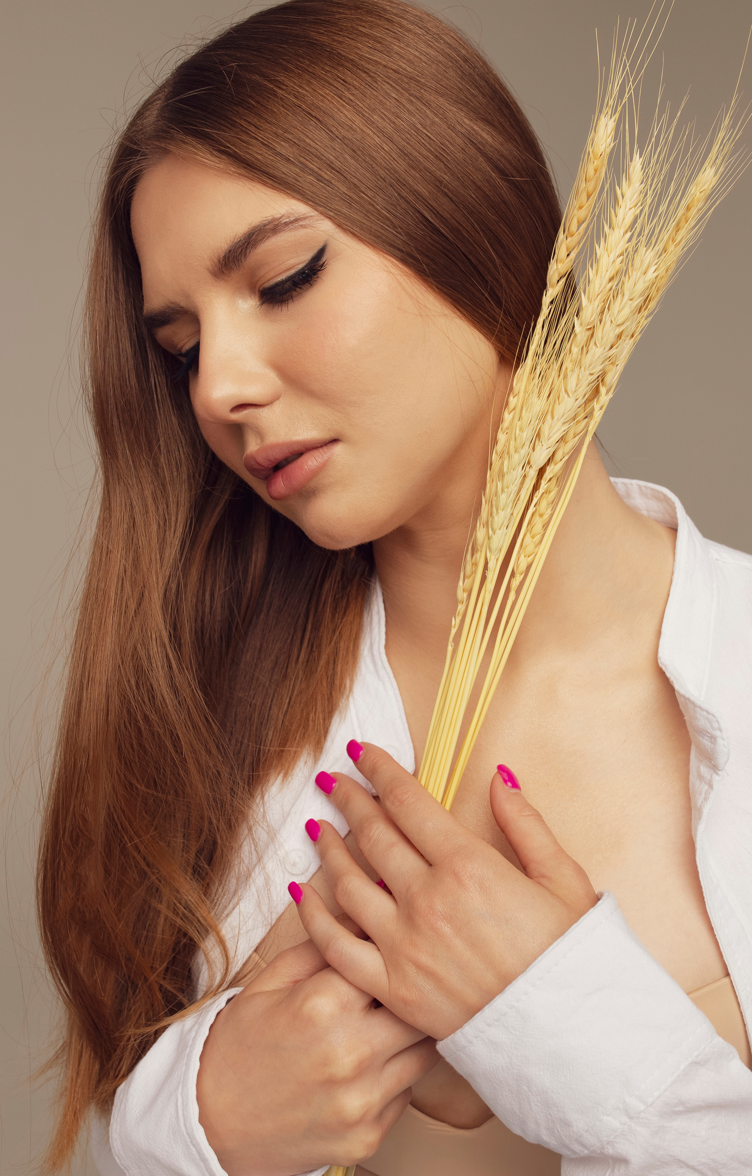 девушка с рыжими волосами в белой футболке и с колосками смотрит вниз