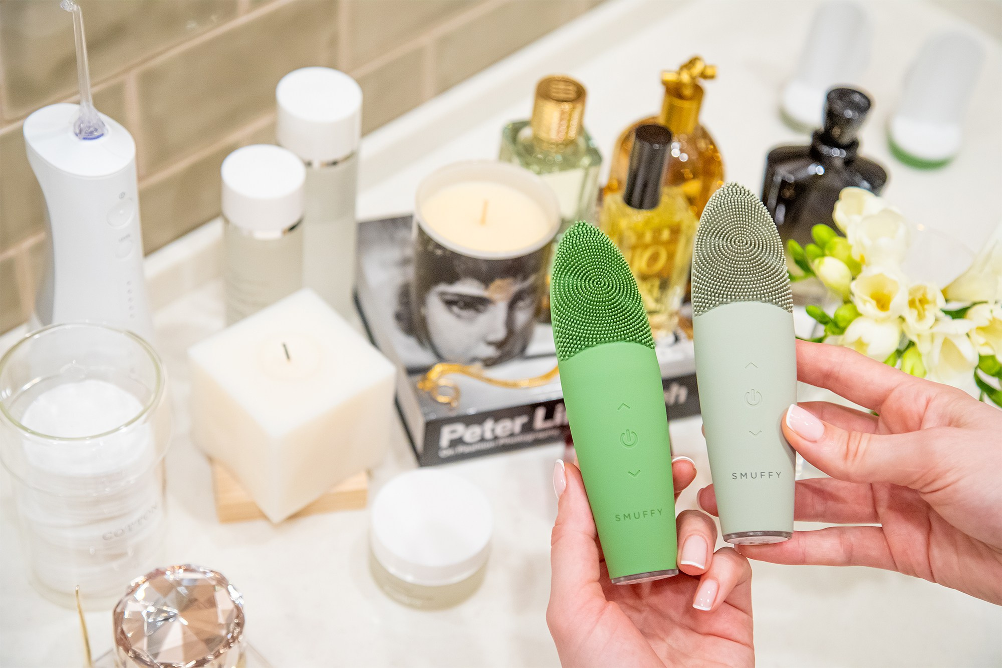 Массажер для лица смуффи в интерьере серо-зеленый и зеленый в руках