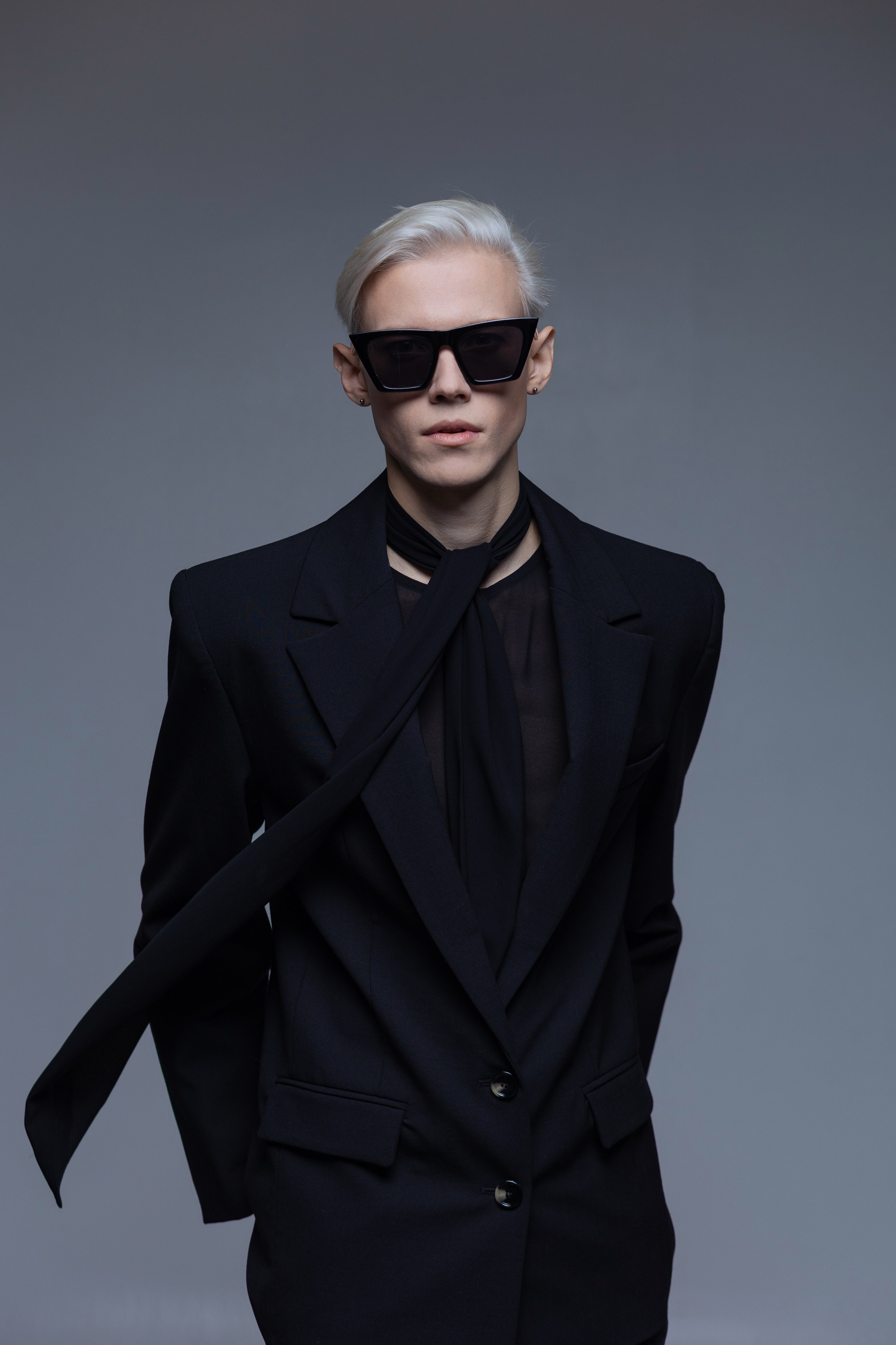 Мужской fashion портрет в чёрных очках и чёрном луке на сером фоне