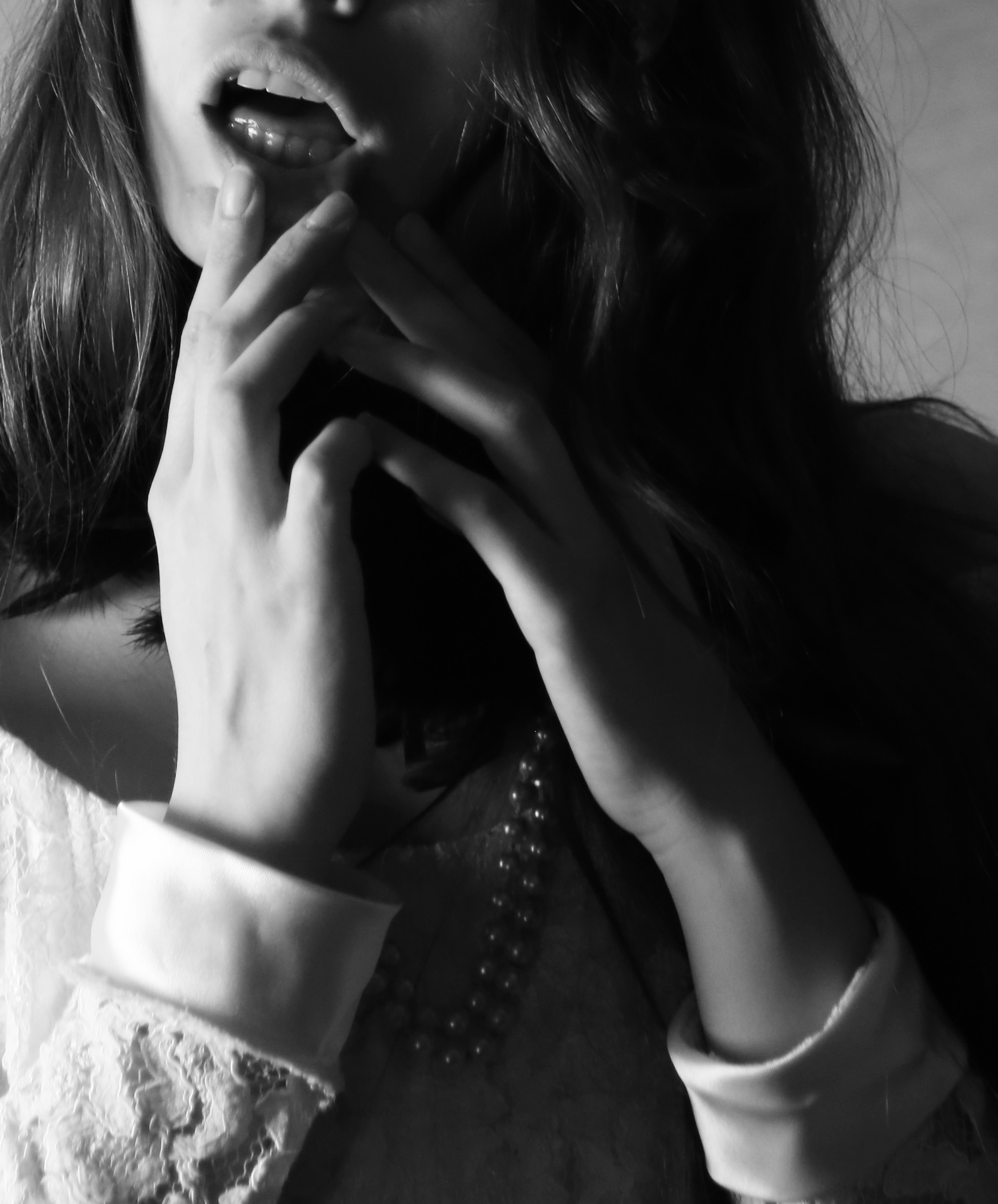 Полуоткрытые губы девушки в белом платье с жемчужными бусами