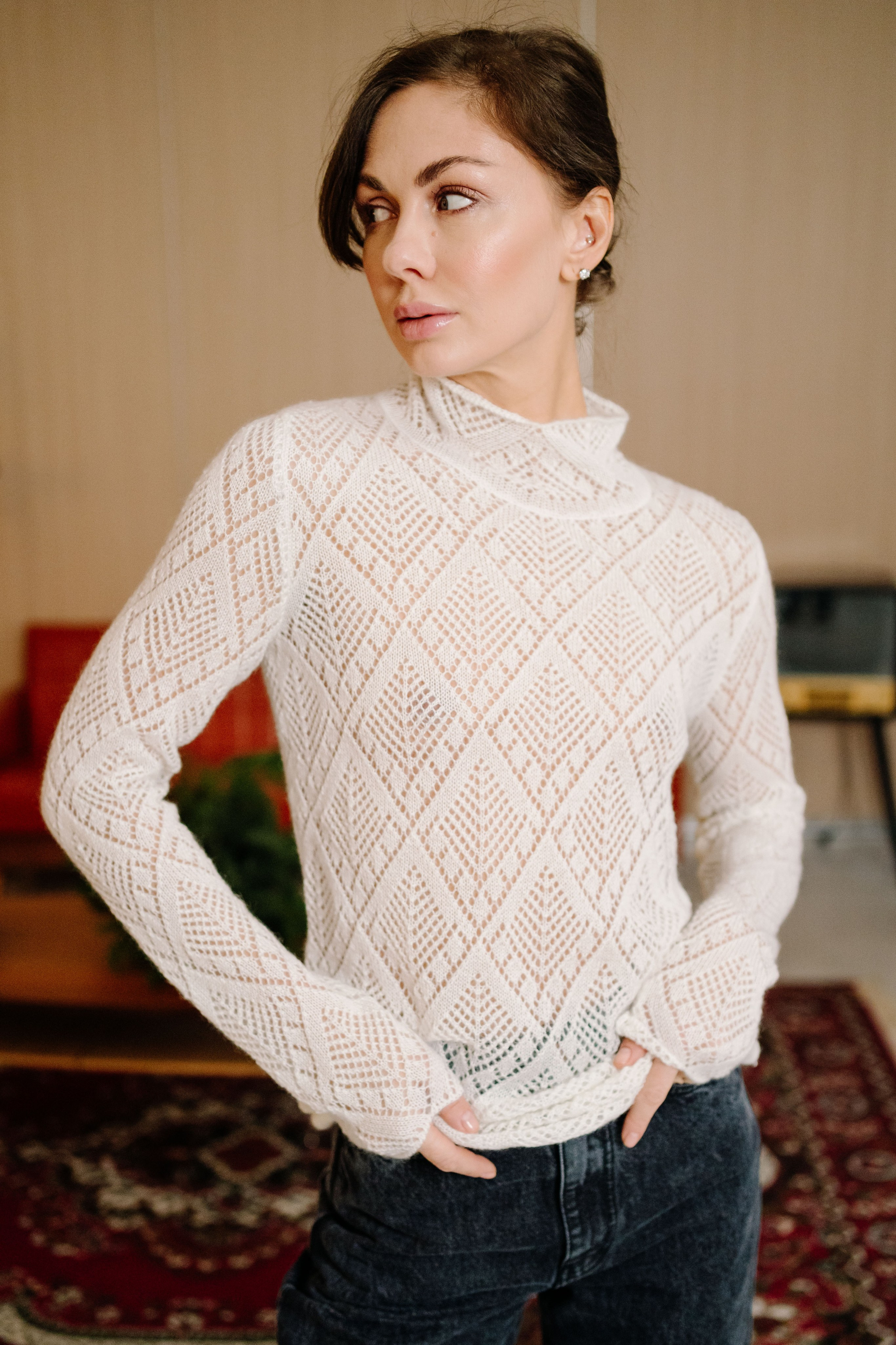 Модель в кружевной блузке позирует в студии