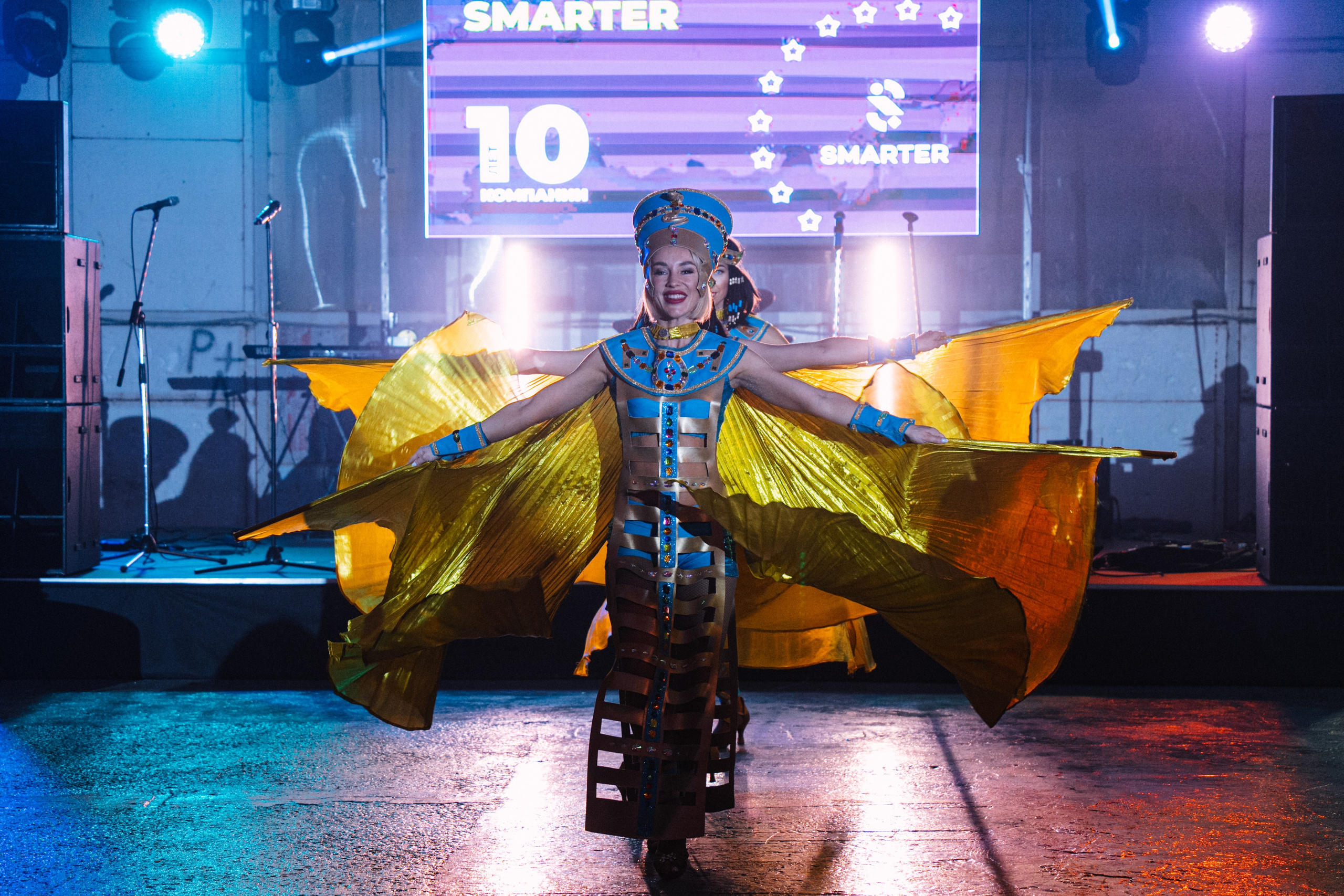Артистка в ярком карнавальном костюме выступает на сцене с перьями и декорациями