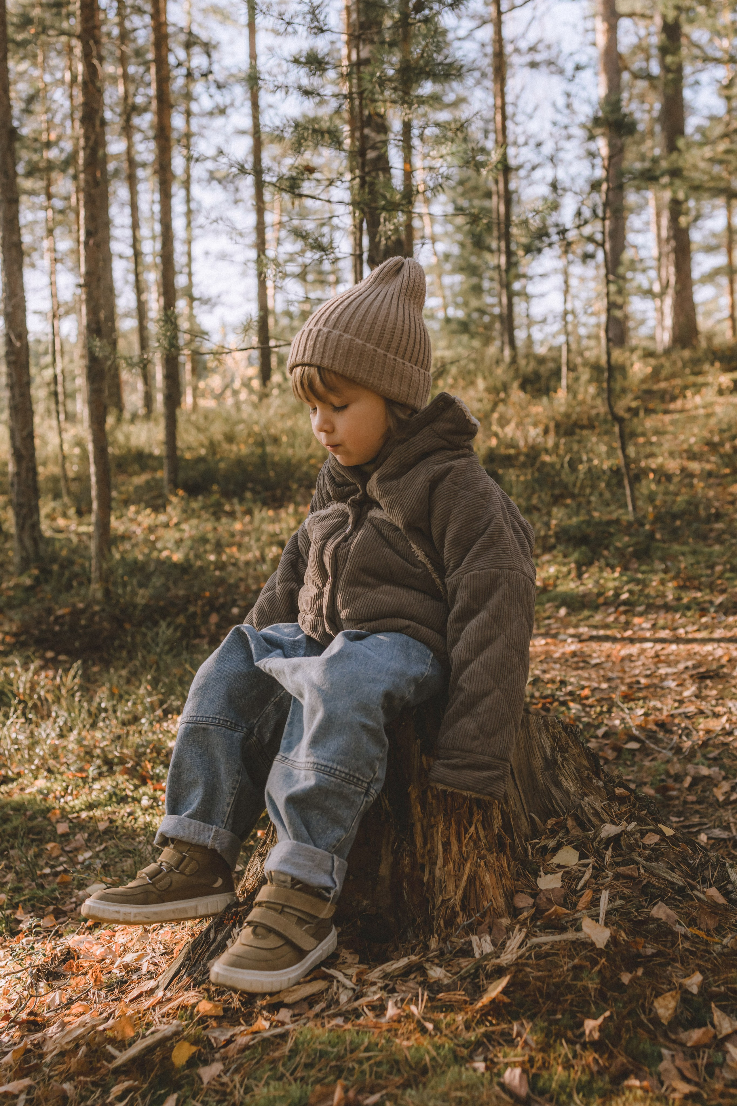 ребенок сидит на пеньке