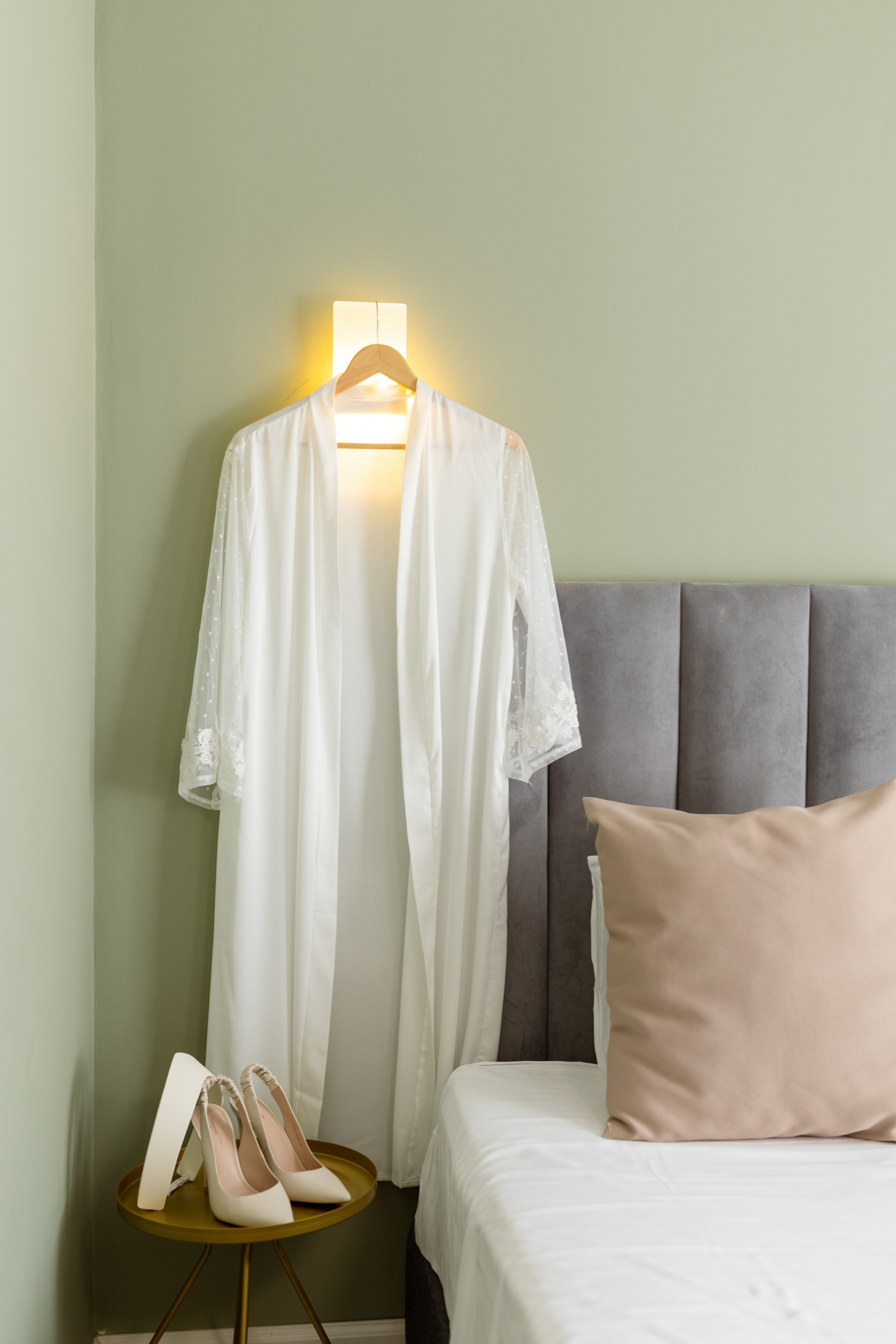 На бра подвешен на тремпеле белый халат, под халатом стоят белые туфли.