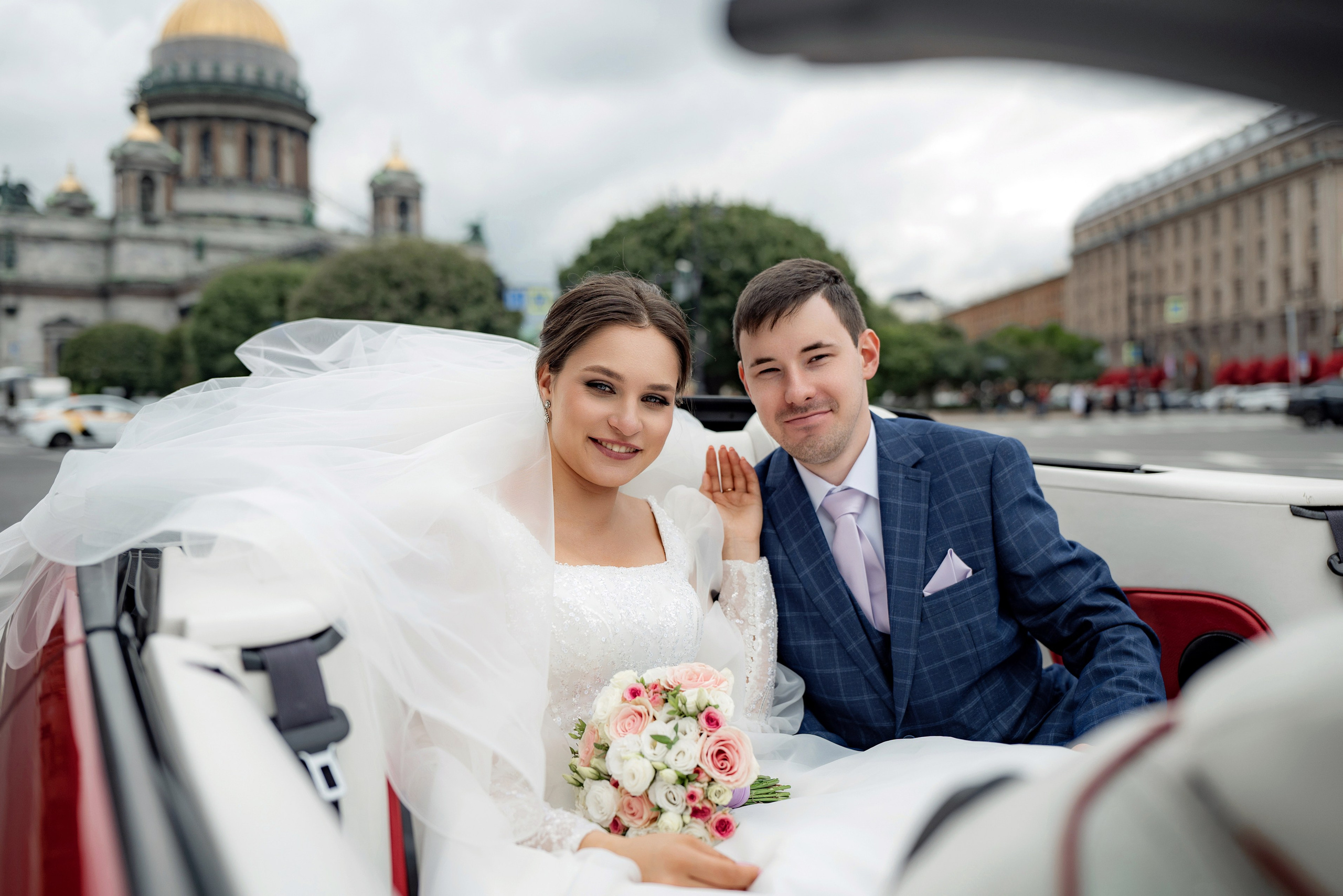 Свадебная фотосессия рядом с Исаакиевским собором на кабриолете. Пара сидит на заднем сидении. Самые популярные места для свадебной фотосессии в Санкт-Петербурге
