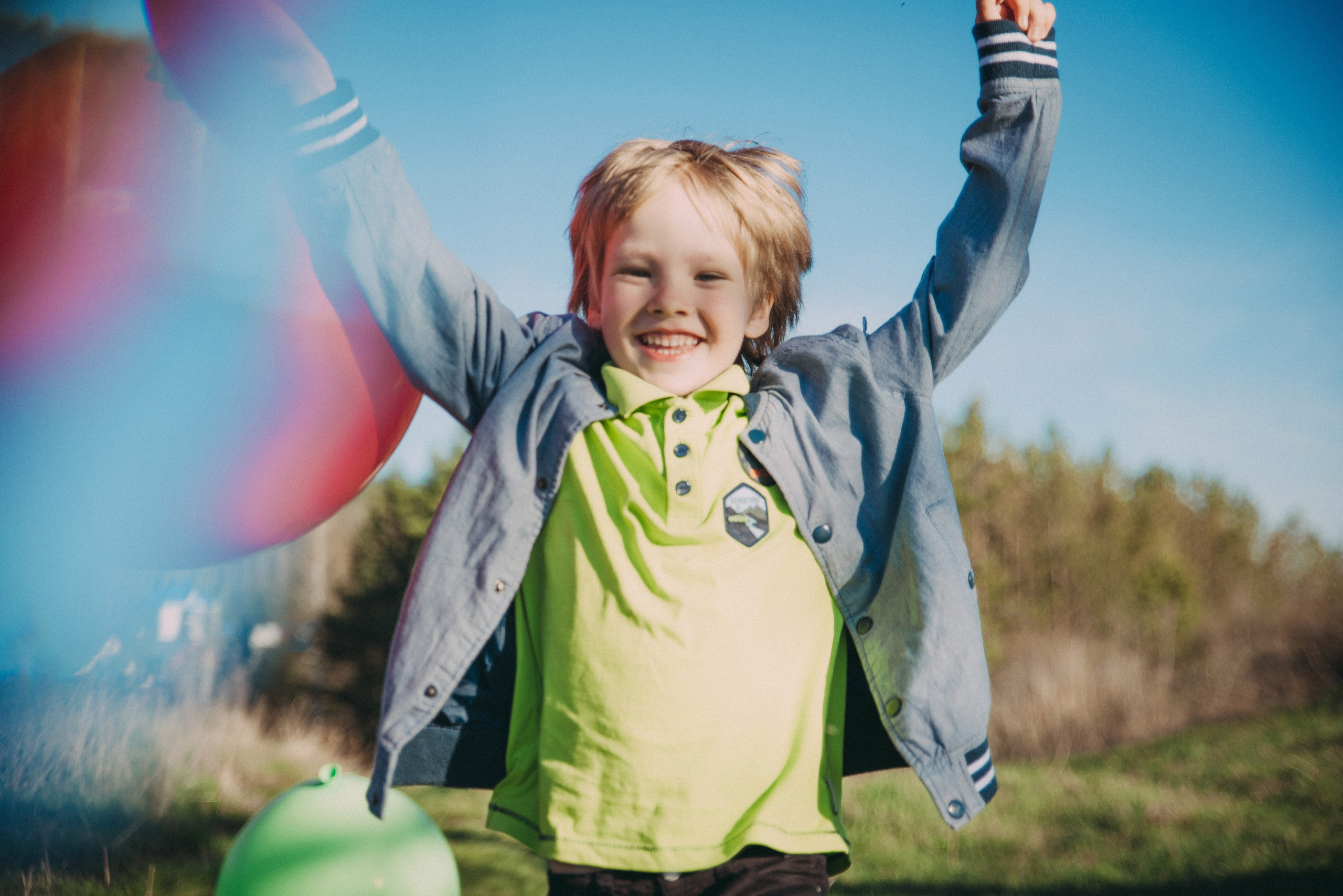 счастливый улыбающийся ребенок с воздушными шарами на природе